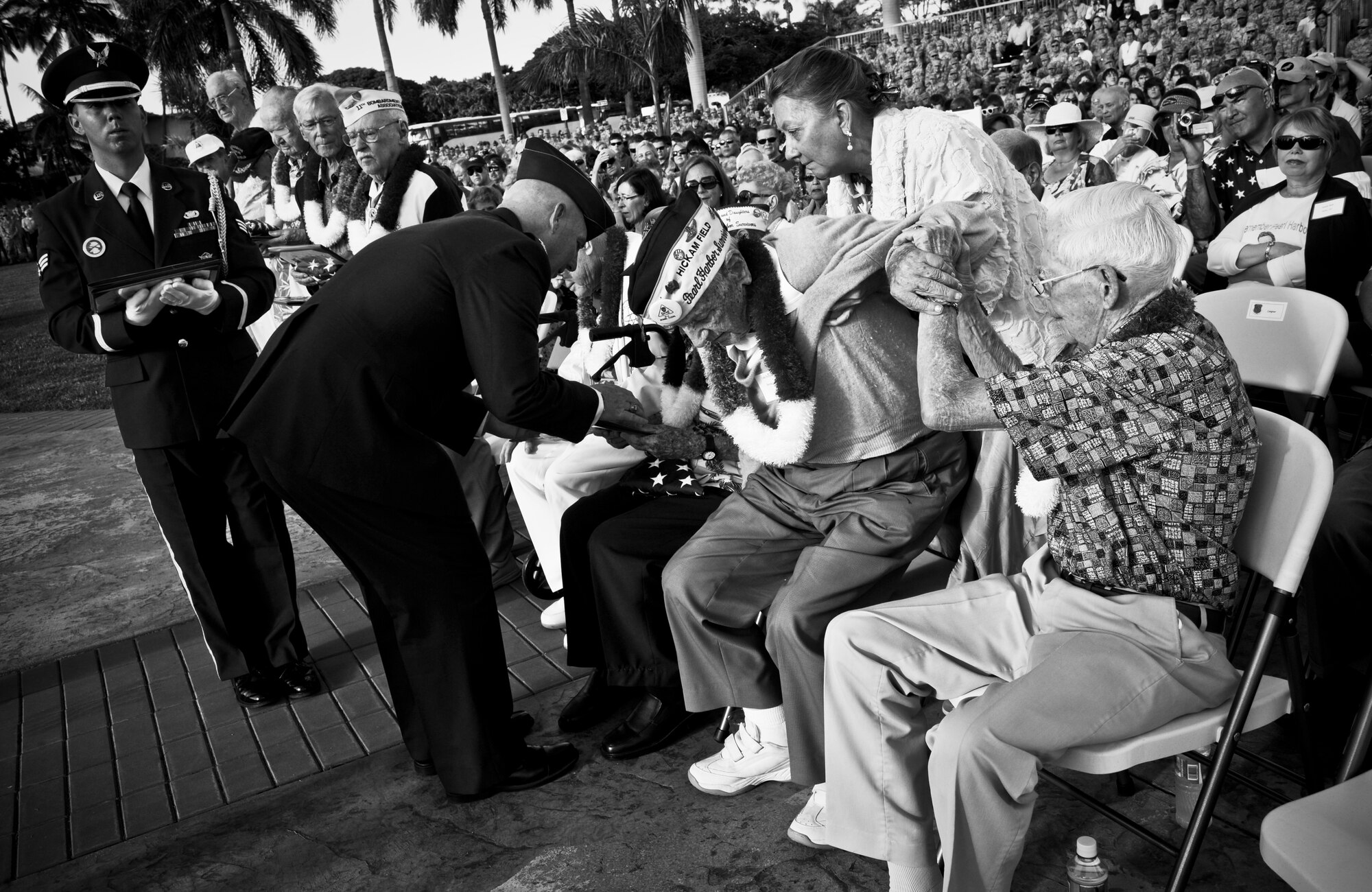 Lou Roffman, a Hickam Field survivor, is helped to his feet by a fellow survivor to accept a certificate from Col. Sam Barrett, 15th Wing commander, at the 70th Anniversary Remembrance Ceremony on Joint Base Pearl Harbor-Hickam, Hawaii, Dec. 7, 2011. Roffman was a B-17 crew chief who went on to risk his life numerous more times throughout World War II, eventually earning a Purple Heart Medal during a flight in which he had to land the B-17after his pilot was killed and his co-pilot was rendered incapable. (U.S. Air Force photo/Senior Airman Lauren Main)