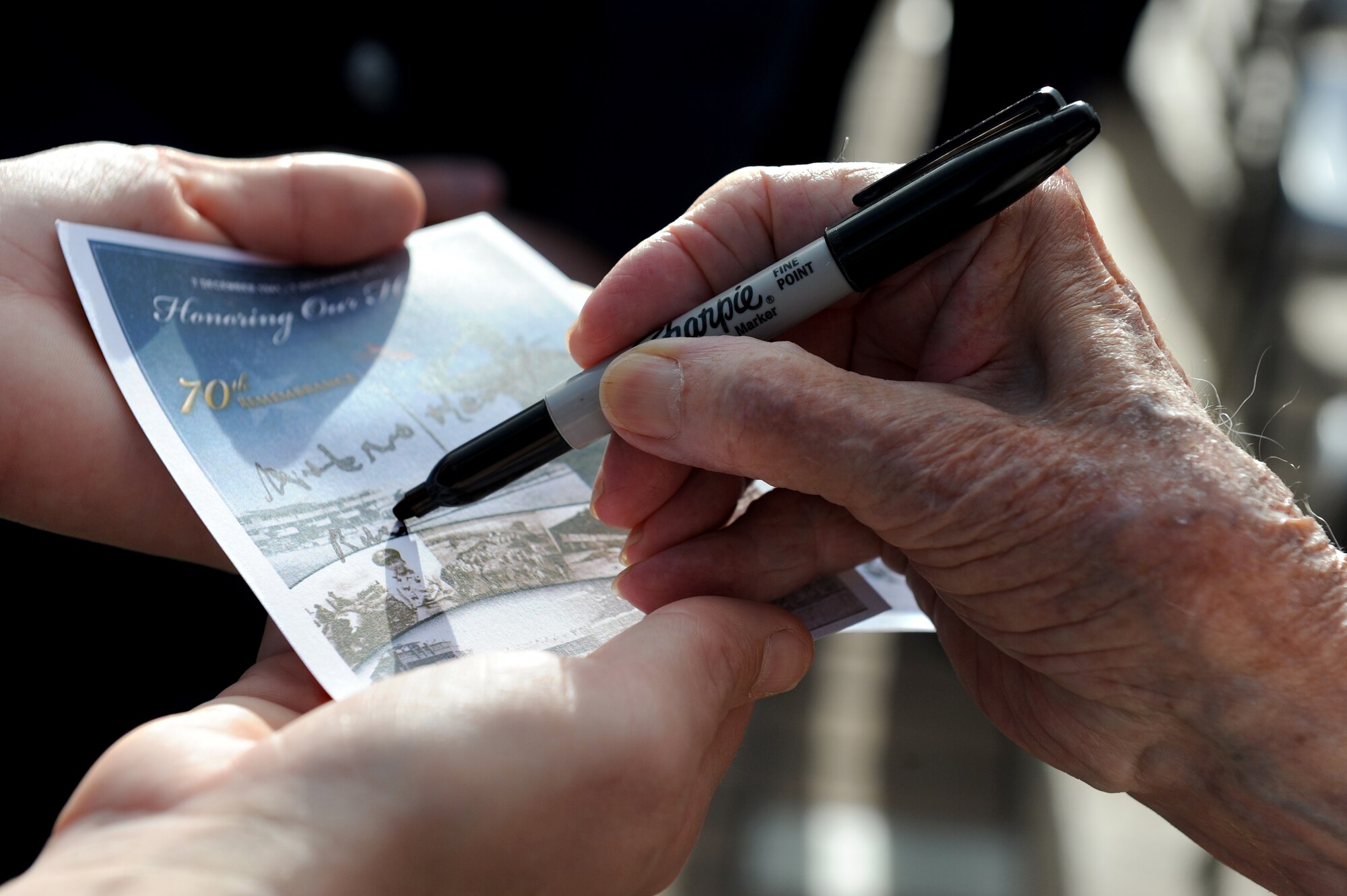 U.S. Air Force (Ret.) Col. Andrew Kowalski, Hickam Field survivor, signs an autograph for someone at the 70th Anniversary Remembrance Ceremony of the attacks on Hickam Field, Dec. 7, 2011. In 1941, Kowalski was the 14th Reconnaissance Squadron first sergeant, and following the attacks, he reported to the Wing building to assist his commander in providing direction and guidance. (U.S. Air Force photo/Staff Sgt. Mike Meares)