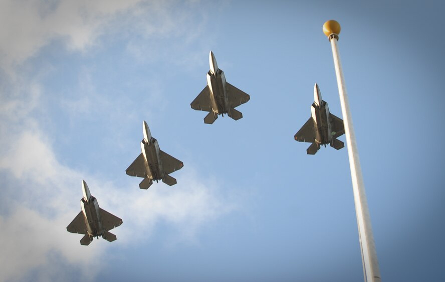 Four F-22 Raptors, assigned to the 19th and 199th Fighter Squadrons, Joint Base Pearl Harbor-Hickam, Hawaii, fly a missing-man formation over the Atterbury Circle flag pole during the 70th Anniversary Remembrance Ceremony, commemorating the attacks on Hickam Field Dec. 7, 1941. (U.S. Air Force photo/Staff Sgt. Mike Meares/Released)