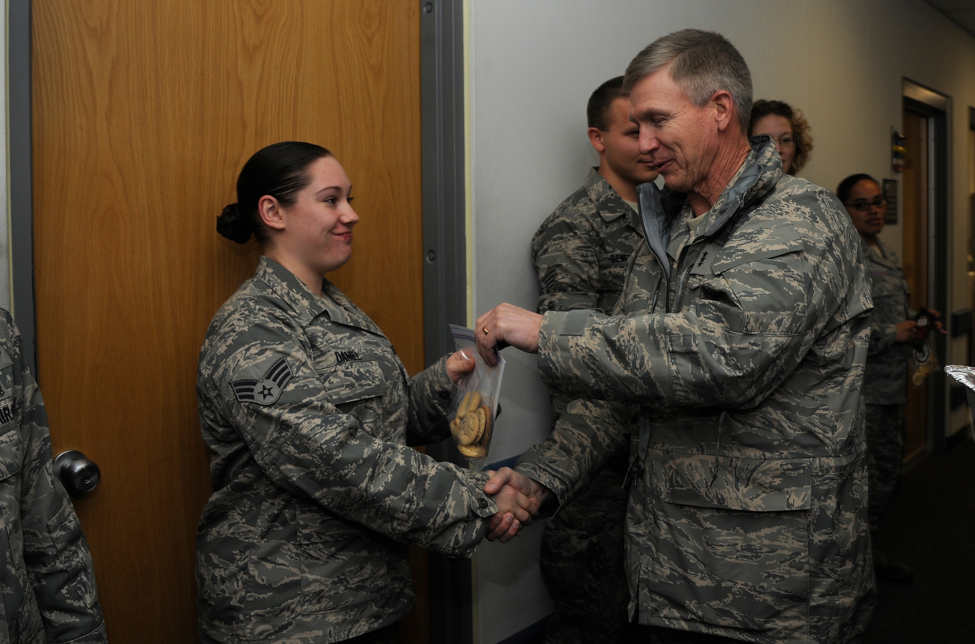 Lt. Gen. Jeffrey A. Remington, 7th Air Force and Air Forces Korea commander, passes cookies to Senior Airman Brandy Baniel, 8th Medical Operations Squadron medical technician, at Kunsan Air Base, Republic of Korea, Dec. 6, 2011. Remington visited Kunsan AB and other bases to distribute 80,000 cookies to Airmen serving in Korea. The cookies were made by a spouses group at Osan Air Base. (U.S. Air Force photo by Staff Sgt. Rasheen Douglas/Released)