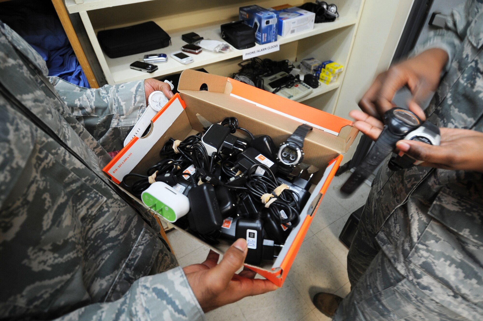 Airmen volunteers at the Wolf Pack Airman’s Attic pull out watches from a box full of cellular chargers, which were donated for other servicemembers to take at Kunsan Air Base, Republic of Korea, Nov. 30, 2011. The attic is open Wednesdays and Thursdays 11 a.m. to 3 p.m. and Saturdays and Sundays 11 a.m. to 3 p.m. (U.S. Air Force photo by Senior Airman Jessica Hines/Released)