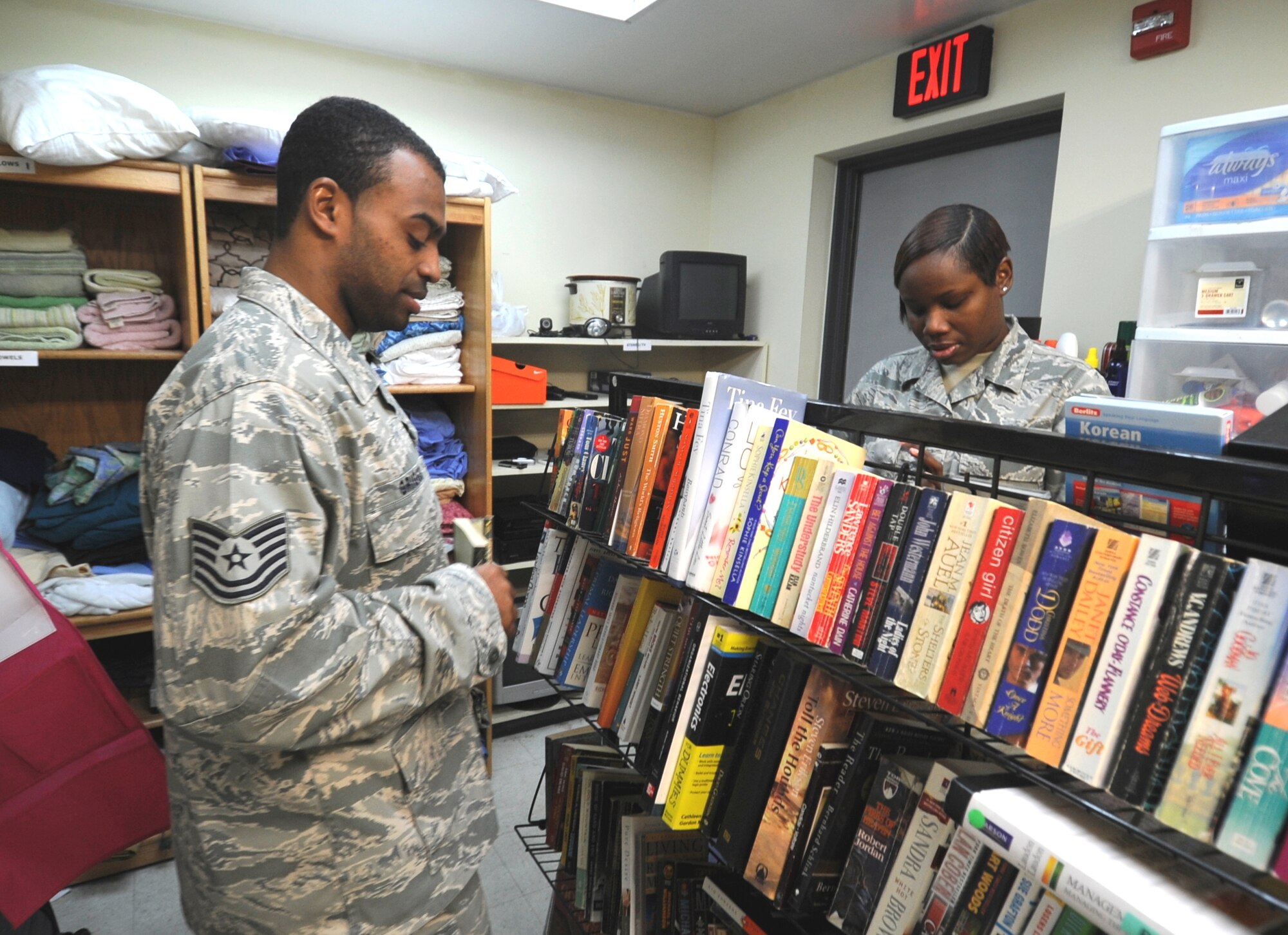 Tech. Sgt. Carlos Griggs, 8th Force Support Squadron manpower analyst, and Tech. Sgt. Tyesha Wilson, 8th Maintenance Operations Squadron scheduler, both volunteers and managers of Wolf Pack Airman’s Attic, straighten up a book shelf at the attic full of books, movies and cassette disks available to Airmen for free at Kunsan Air Base, Republic of Korea, Nov. 30, 2011. The Wolf Pack Airman’s Attic is open Wednesdays and Thursdays 11 a.m. to 3 p.m. and Saturdays and Sundays 11 a.m. to 3 p.m. (U.S. Air Force photo by Senior Airman Jessica Hines/Released)