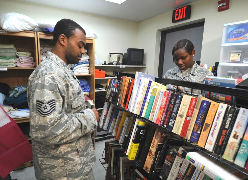Tech. Sgt. Carlos Griggs, 8th Force Support Squadron manpower analyst, and Tech. Sgt. Tyesha Wilson, 8th Maintenance Operations Squadron scheduler, both volunteers and managers of Wolf Pack Airman’s Attic, straighten up a book shelf at the attic full of books, movies and cassette disks available to Airmen for free at Kunsan Air Base, Republic of Korea, Nov. 30, 2011. The Wolf Pack Airman’s Attic is open Wednesdays and Thursdays 11 a.m. to 3 p.m. and Saturdays and Sundays 11 a.m. to 3 p.m. (U.S. Air Force photo by Senior Airman Jessica Hines/Released)