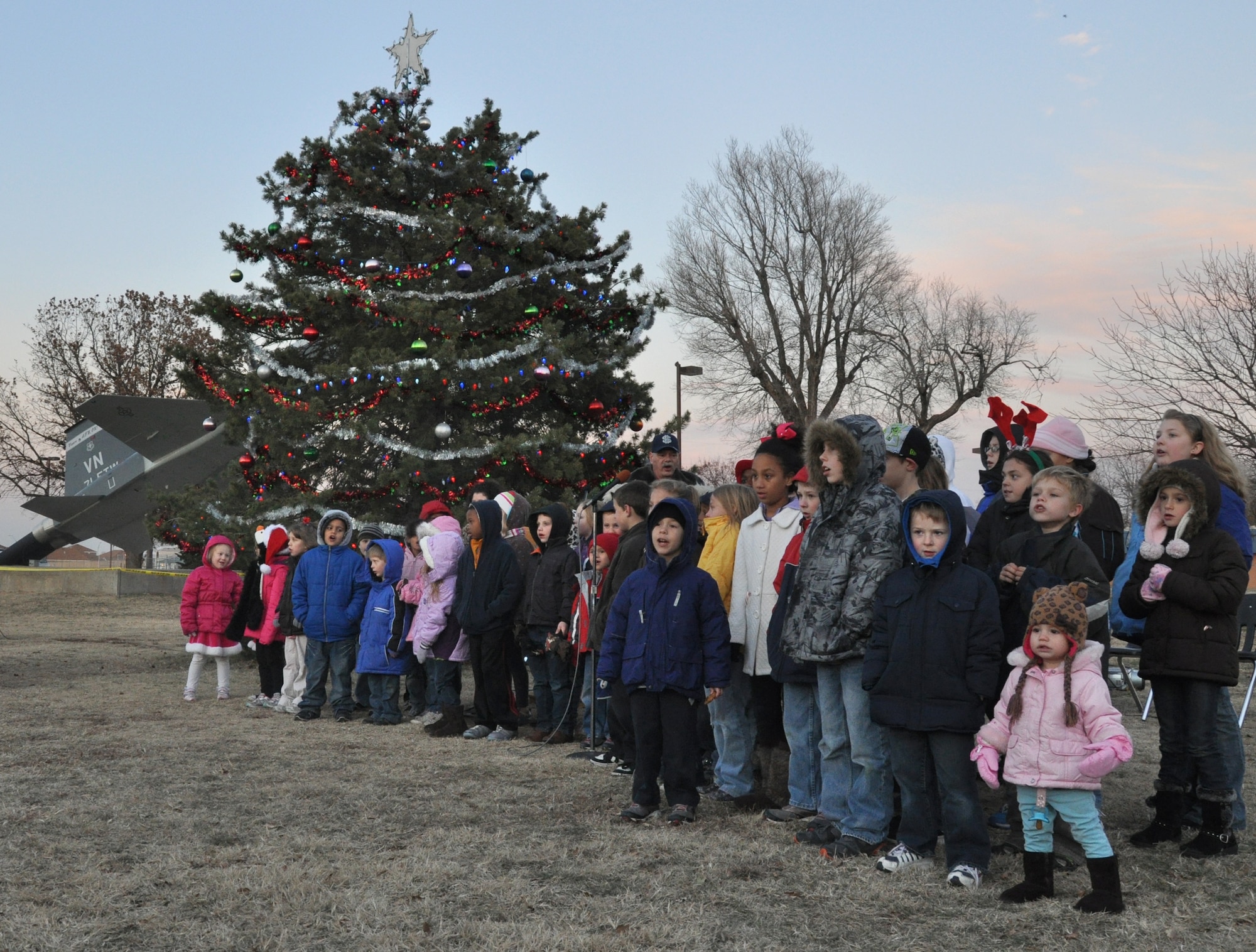 The Eisenhower Elementary School Honor Chorus class sings holiday songs during the Tree lighting ceremony Dec. 2 at Vance Air Force Base, Okla. More than 235 attended the ceremony. The Team Vance members and their families consumed 200 cookies and 18 gallons of hot chocolate. Displays of Air Force equipment and Army vehicles from the 401st Army Engineer Company were set up for the attendees to view. (U.S. Air Force photo/ Airman 1st Class Frank John Casciotta)
