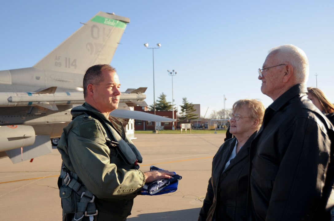 Lt. Col. Tim Moses, 180th FW Operations Support Squadron Commander, presented Walter Young with an Air Force flag in honor of Young's son, Lt. Mike Young. Moses carried with him an American flag and a United States Air Force flag and flew up the coast of Lake Huron and over the crash site, where a memorial in Lt. Young’s name now stands.180th Fighter Wing members, along with family and friends of pilot, Lt. Mike Young gathered for a small memorial honoring the pilot, 20 years after Young died when his A-7 Corsair crashed during a routine training mission. The group gathered at the 180th Fighter Wing, Ohio Air National Guard Base, Swanton, OH, Nov. 30.