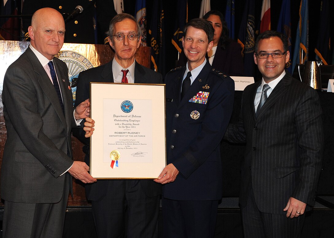 Dr. Robert Rudney receives his Department of Defense Outstanding Employee with a Disability award Dec. 6, 2011, from John R. Campbell, Lt. Gen. Darrell Jones and Daniel Ginsberg during the 31st Annual DOD Disability Awards ceremony at the Hyatt Regency Hotel in Bethesda, Md. The award highlights the valuable contributions to national security made by individuals with disabilities. Rudney is the senior adviser and learning integration research liaison, Campell is the Deputy Assistant Secretary of Defense for Wounded Warrior Care and Transition Policy, Jones is the Air Force deputy chief of staff for manpower, personnel and services and Ginsberg is the Air Force assistant secretary for manpower and reserve affairs. (U.S. Air Force photo/Master Sgt. Raheem Moore)