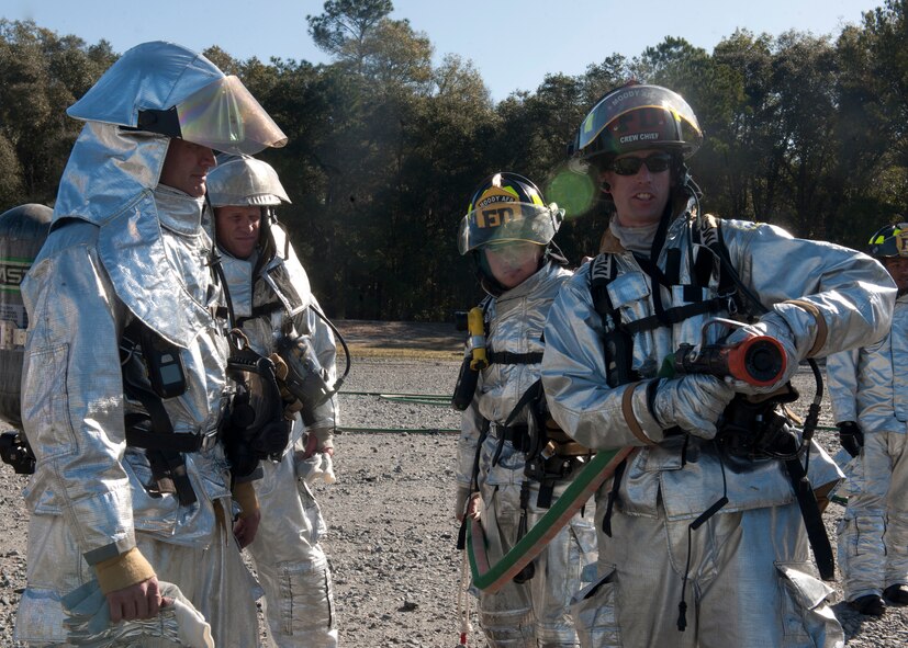 Members of the 23rd Civil Engineer Squadron fire department demonstrate to U.S. Air Force Col. Billy Thompson, 23rd Wing commander, and Chief Master Sgt. Frank Batten, 23rd Wing command chief, on how to hold and aim a fire hose during a fire fighter exercise at Moody Air Force Base, Ga., Dec. 5, 2011. Thompson and Batten were shown first-hand what it’s like to be an Air Force fire fighter by entering a live burning “aircraft,” where they worked with 23rdd CES Airmen to help put a fire out. (U.S. Air Force photo by Senior Airman Eileen Meier/Released)

