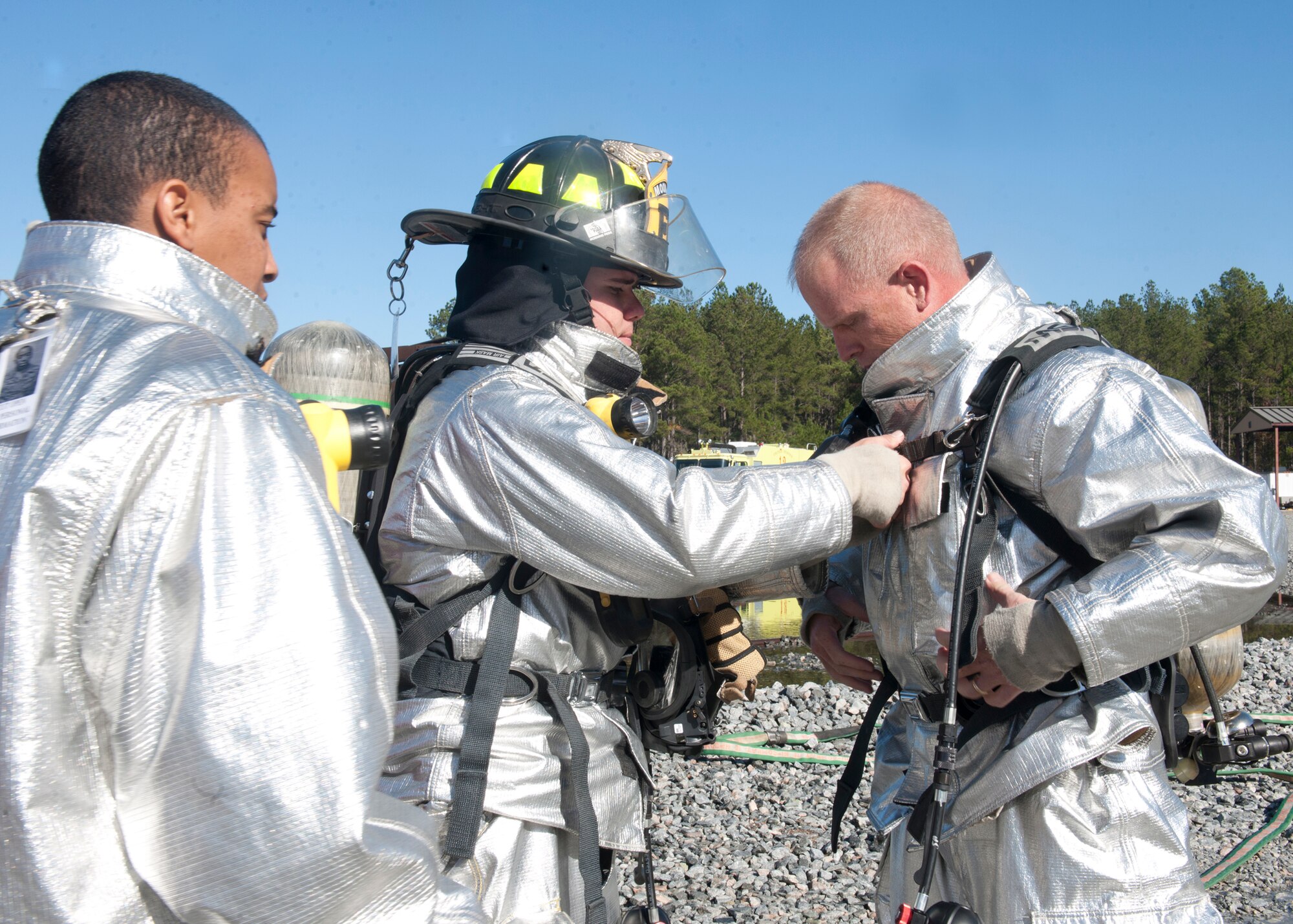 Members of the 23rd Civil Engineer Squadron fire department assist U.S. Air Force Chief Master Sgt. Frank Batten, 23rd Wing command chief, to put on his personal protective equipment prior to a fire fighter training session at Moody Air Force Base, Ga., Dec. 5, 2011. Along with Batten and the Airmen of the 23rd CES, Col. Billy Thompson, 23rd Wing commander, participated in the exercise to experience first-hand the duty of an Air Force fire fighter. (U.S. Air Force photo by Senior Airman Eileen Meier/Released)