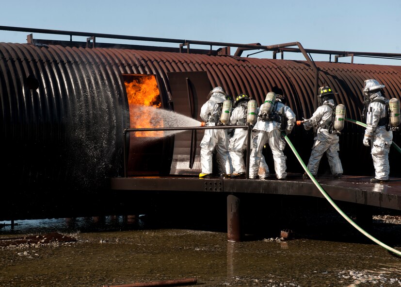 Members of the 23rd Civil Engineer Squadron fire department work to put out a fire at a training site called “The Pit” at Moody Air Force Base, Ga., Dec. 5, 2011. U.S. Air Force Col. Billy Thompson, 23rd Wing commander, and Chief Master Sgt. Frank Batten, 23rd Wing command chief, were also in the training and went in first to fight the fire. The burning structure was a simulated downed aircraft. (U.S. Air Force photo by Senior Airman Eileen Meier/Released)