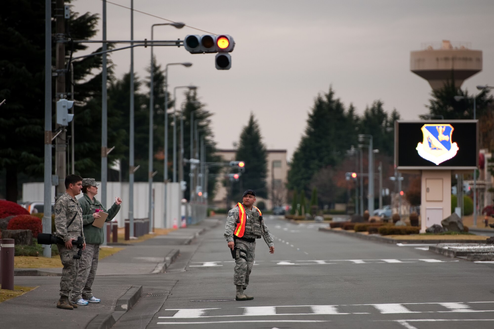 YOKOTA AIR BASE, Japan -- (Left to right) Staff Sgt. Samuel Morse and Tech. Sgt. Robin Stanchak, both members of the 374th Airlift Wing public affairs office, coordinate with Tech. Sgt. Alberto Verastegui, a 374th Security Forces Squadron patrolman, to gain entry into a cordoned-off area following the discovery of an unexploded ordnance on Yokota Air Base, Japan, Dec. 6, 2011. (U.S. Air Force photo/Osakabe Yasuo)