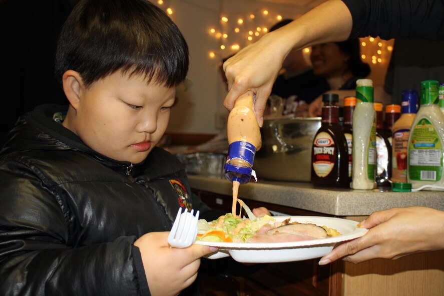 Wolf Pack members serve children from the Ilmagwon Orphanage at the base chapel’s SonLight Inn for dinner during their visit for a Christmas party at Kunsan Air Base, Republic of Korea, Dec. 3, 2011. With open arms, 63 Wolf Pack members graciously welcomed the orphans to their home for an afternoon of fun, games, food and presents. (U.S. Air Force photo by Staff Sgt. Robert Webb/Released)