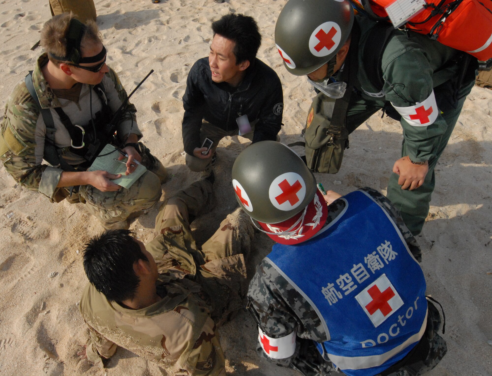 U.S. Air Force members of the 31st Rescue Squadron and the Japanese Air Self Defense Force  work to secure and treat a simulated patient  during the Cope Angel exercise in Okinawa, Japan, Dec. 5, 2011.This bilateral exercise is used to increase combat readiness, highlight interoperability amongst the Japanese and U.S forces. (U.S. Air Force photo by Tech. Sgt. Lakisha A. Croley/Released) 