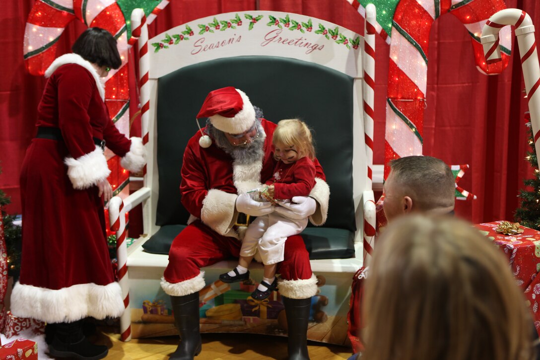 Annessa sits on Santa's lap as he calmly listens to what she wants to find under the Christmas tree this year during the Headquarters and Support Battalion Holiday Jubilee at the Geottge Memorial Field House aboard Marine  Corps Base Camp Lejeune, Dec. 8. The jubilee was hosted to bring families closer together, increase camaraderie among service members and boost morale