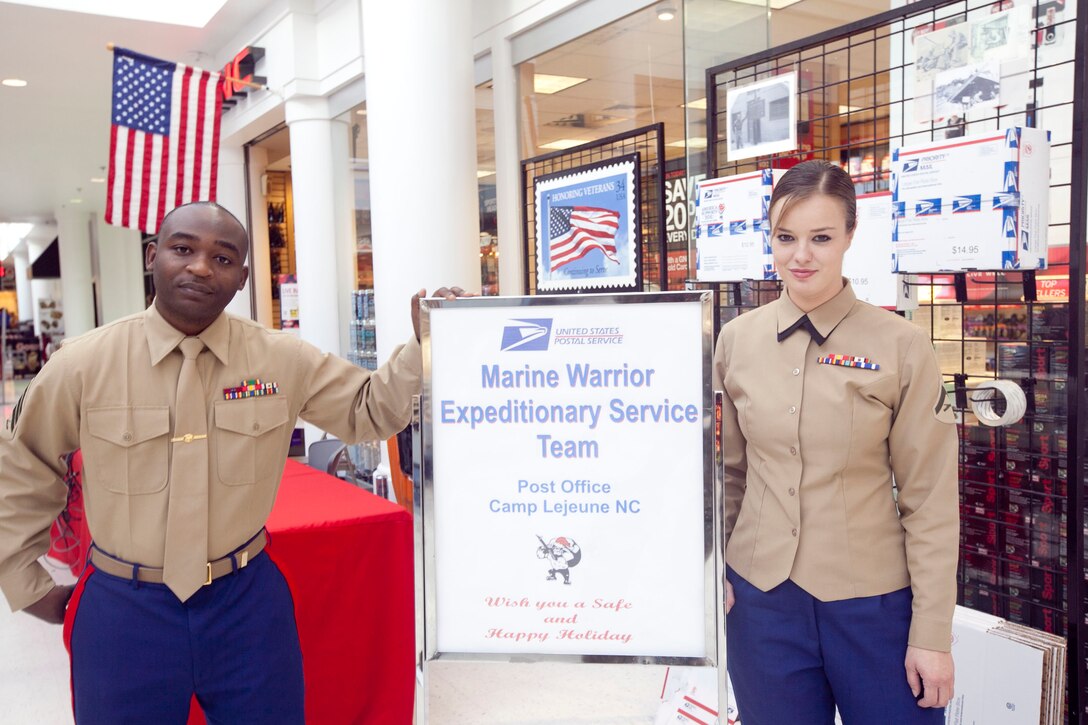 Sgt. Robert Lismore, the postal clerk and noncommissioned officer in charge with the Courthouse Bay post office and Lance Cpl. Jessie Hart, the finance clerk with Courthouse Bay post office pose in front of the Warrior Express Service Team stand, which provided postal service in the Marine Corps Exchange aboard Marine Corps Base Camp Lejeune, Dec. 12. The WES Team was set up to alleviate the congestion found in other post offices during the holiday.