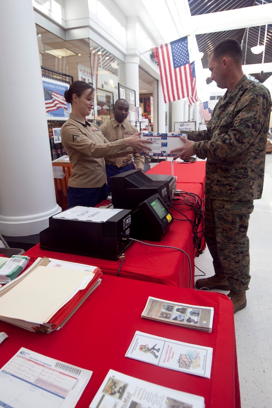 A Marine hands a package to Lance Cpl. Jessie Hart, the finance clerk with Courthouse Bay post office at the Warrior Express Service Team stand, which provided postal service in the Marine Corps Exchange aboard Marine Corps Base Camp Lejeune, Dec. 12. The WES Team provided postal service from Dec.  6 through Dec. 10 and Dec. 13 through 17.