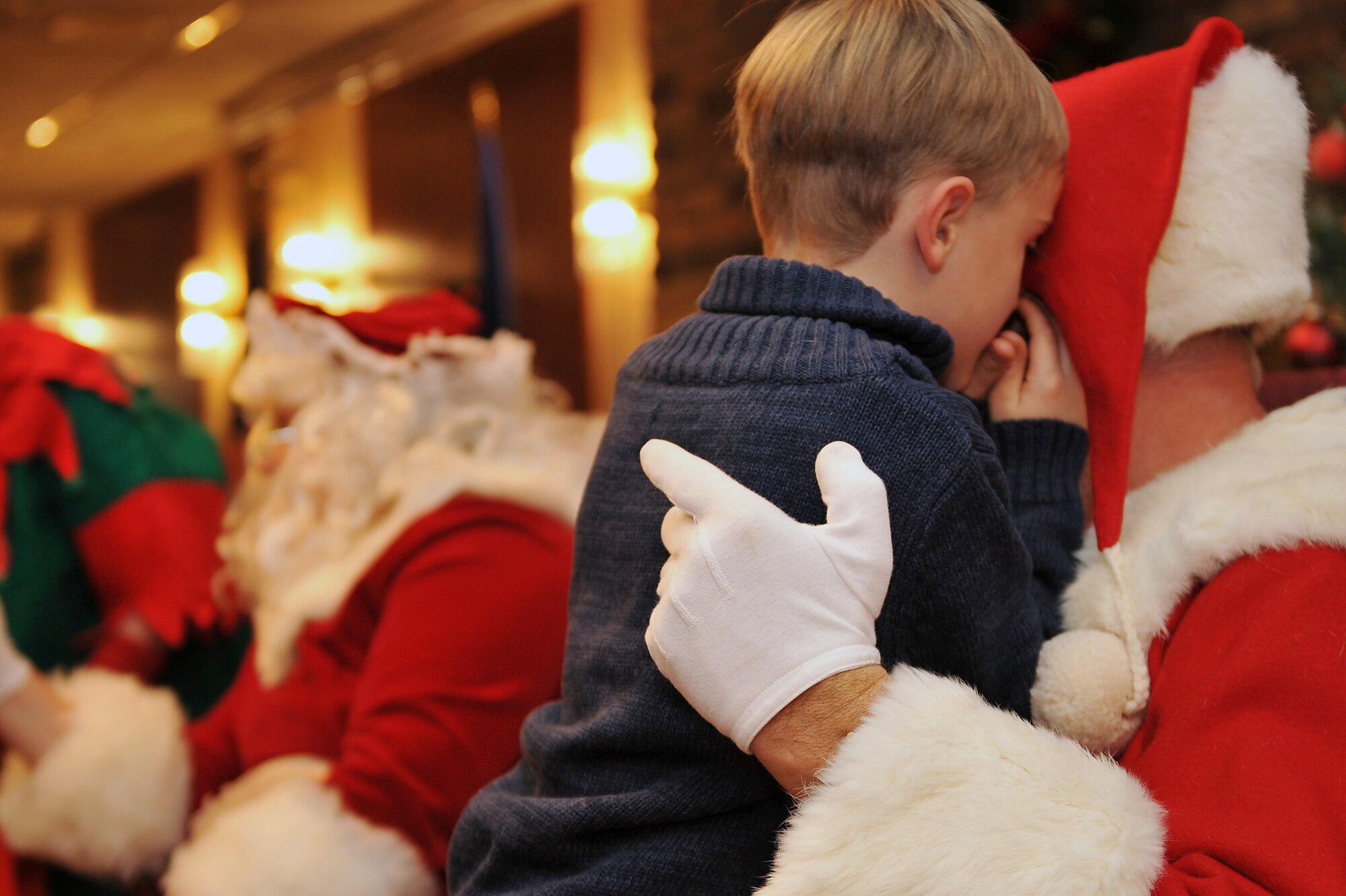 Harper Kean, the son of 2nd Lt. Christopher Kean assigned to the Air Combat Command Training Support Squadron, whispers to Santa Dec. 1, 2011, at Offutt Air Force Base, Neb. Members from the base and their families watched a tree lighting ceremony followed by holiday activities at the community activity center. (U.S. Air Force photo/Jeff Gates)
