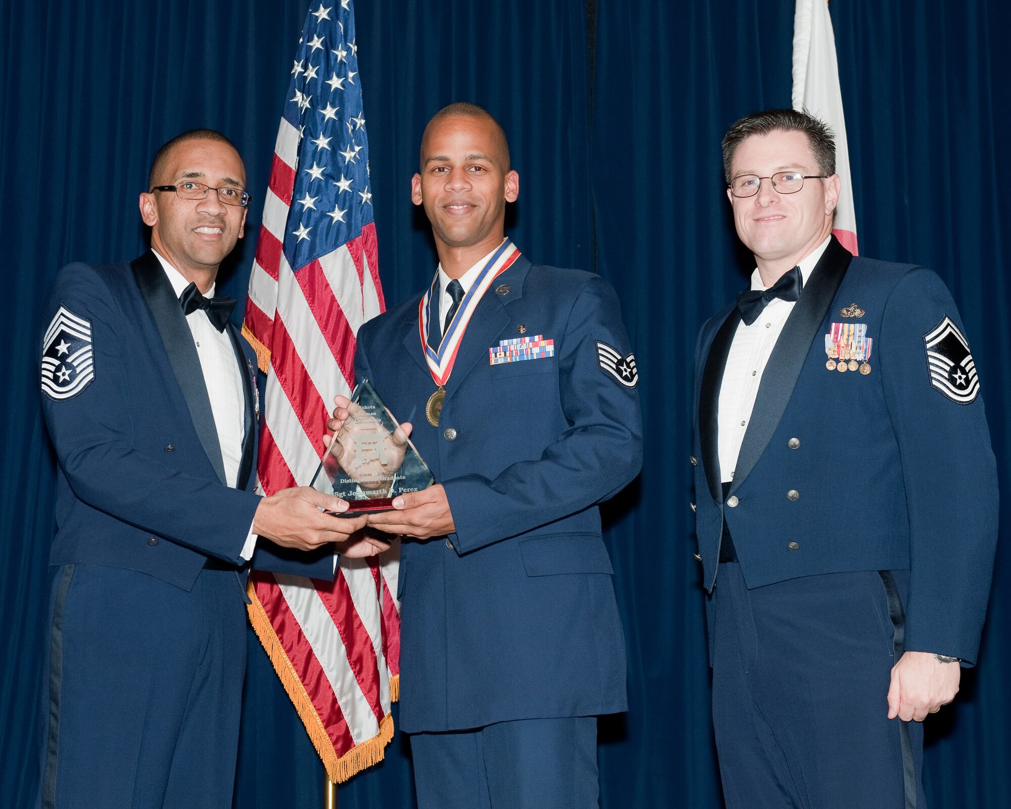 YOKOTA AIR BASE, Japan -- Staff Sgt. Johnmarth Perez (center), 374th Medical Support Squadron, is awarded the Distinguished Graduate Award during the Airman Leadership School Class 12-A graduation ceremony at Yokota Air Base, Japan, Dec. 8, 2011. Command Chief Master Sgt. Ronald Draper (left), 374th Airlift Wing, and Senior Master Sgt. Dean Wilson (right), 374th Civil Engineer Squadron, representatives of the Civil Engineering Association, presented the award to Perez during the ceremony. (U.S. Air Force photo/Osakabe Yasuo)