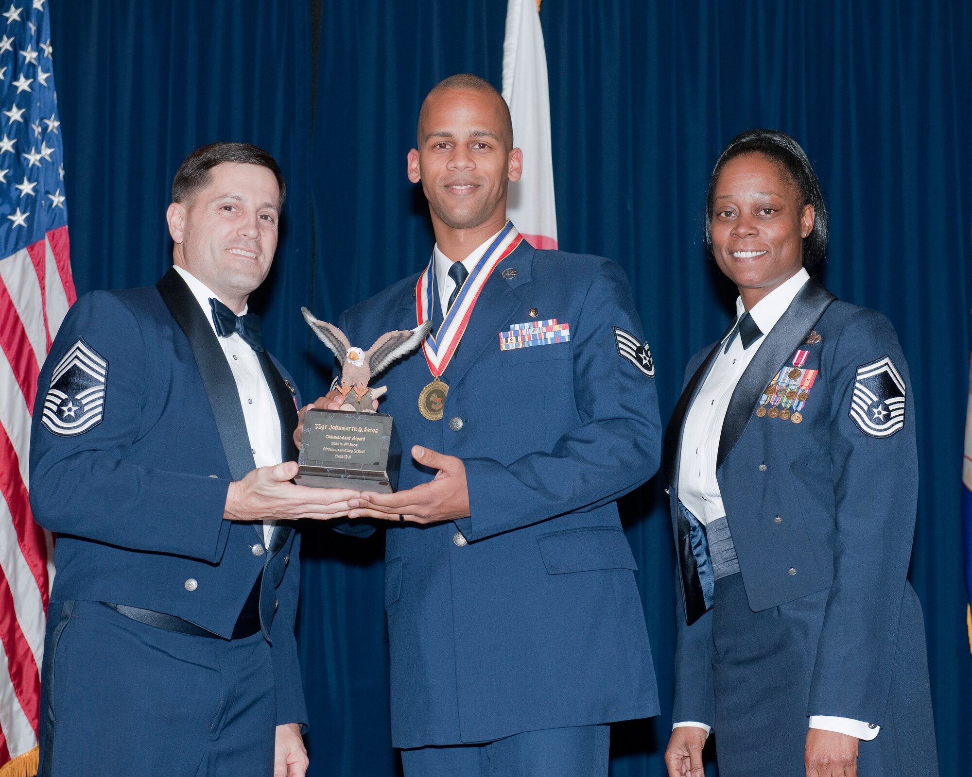 YOKOTA AIR BASE, Japan -- Staff Sgt. Johnmarth Perez (center), 374th Medical Support Squadron, is awarded the Commandant Award during the Airman Leadership School Class 12-A graduation ceremony at Yokota Air Base, Japan, Dec. 8, 2011. Chief Master Sgt. James Cornell (left), 374th Maintenance Group, and Senior Master Sgt. Nanette Klingaman (right), 374th Force Support Squadron, representatives of the Yokota's Chief's Group, presented the award to Perez during the ceremony. (U.S. Air Force photo/Osakabe Yasuo)
