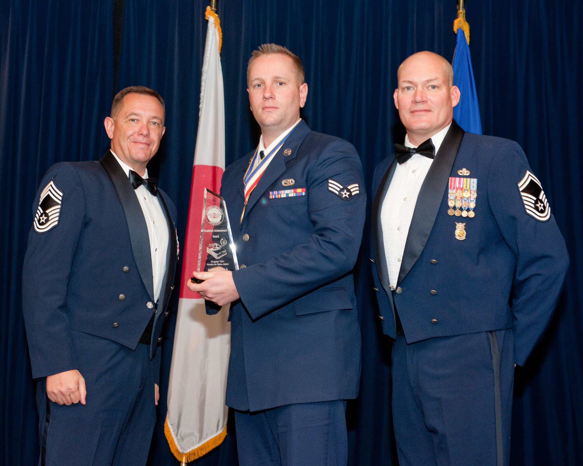 YOKOTA AIR BASE, Japan -- Senior Airman John Sadler (center), 374th Maintenance Squadron, is awarded the Academic Award during the Airman Leadership School Class 12-A graduation ceremony at Yokota Air Base, Japan, Dec. 8, 2011. Chief Master Sgt. Terry Webb (left), 374th Aircraft Maintenance Squadron, and Senior Master Sgt. Kevin Riehle (right), 374th Civil Engineer Squadron, representatives of the Air Force Sergeants Association, presented the award to Sadler during the ceremony. (U.S. Air Force photo/Osakabe Yasuo)