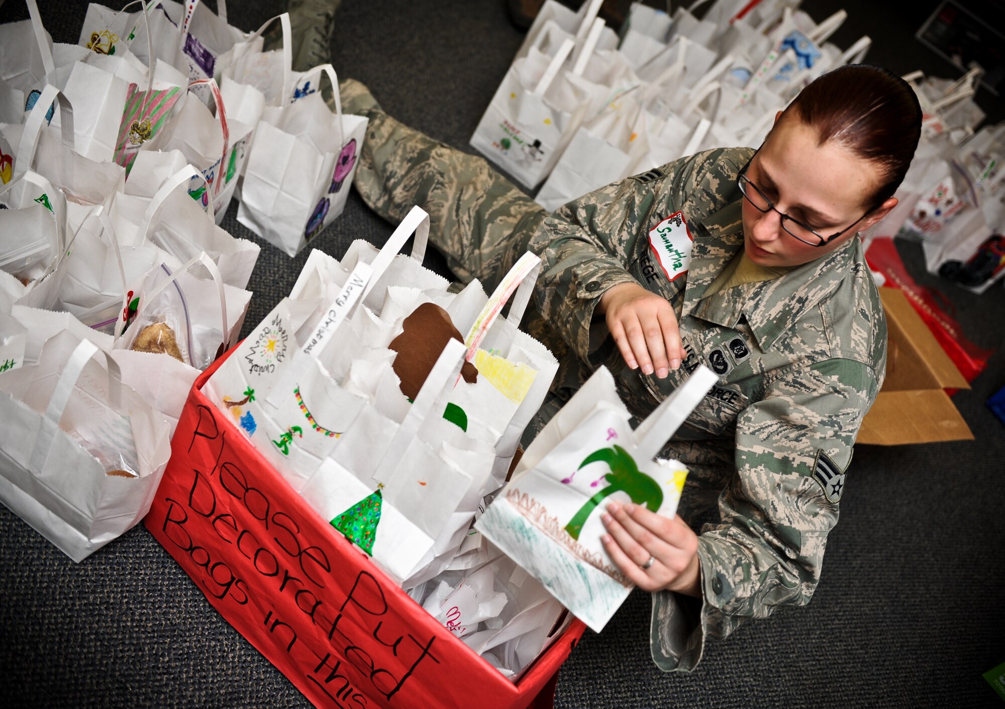 Senior Airman Samantha Strege, emergency management journeyman with the 647th Civil Engineering Squadron, packs boxes full of bags of cookies for first sergeants to give out to single Airmen in the dorms at Joint Base Pearl Harbor-Hickam, Hawaii,  for the annual Cookie Caper, Dec. 8. Friends of Hickam, as well as Hickam Federal Credit Union made large donations of multiple different types of cookies. (U.S. Air Force photo/Senior Airman Lauren Main)