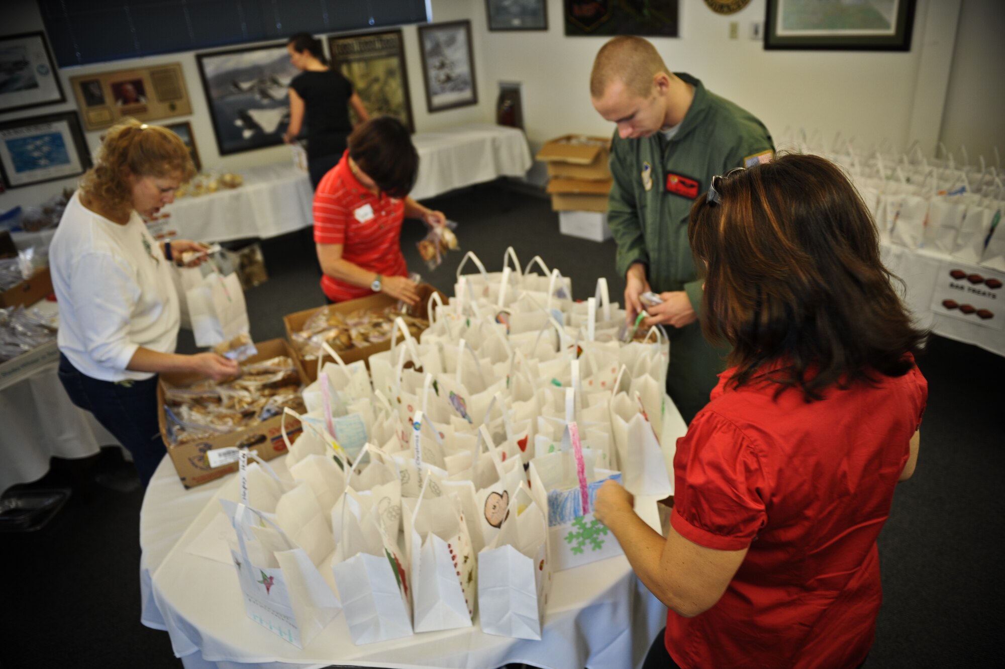 Volunteers for the annual Cookie Caper disseminate cookies into decorated bags for single Airmen in the dorms on Joint Base Pearl Harobr-Hickam, Hawaii, Dec. 8. The colorfully decorated bags were designed by elementary school students from Mokulele Elementary, Hickam Elementary and Nimitz Elementary. (U.S. Air Force photo/Senior Airman Lauren Main)