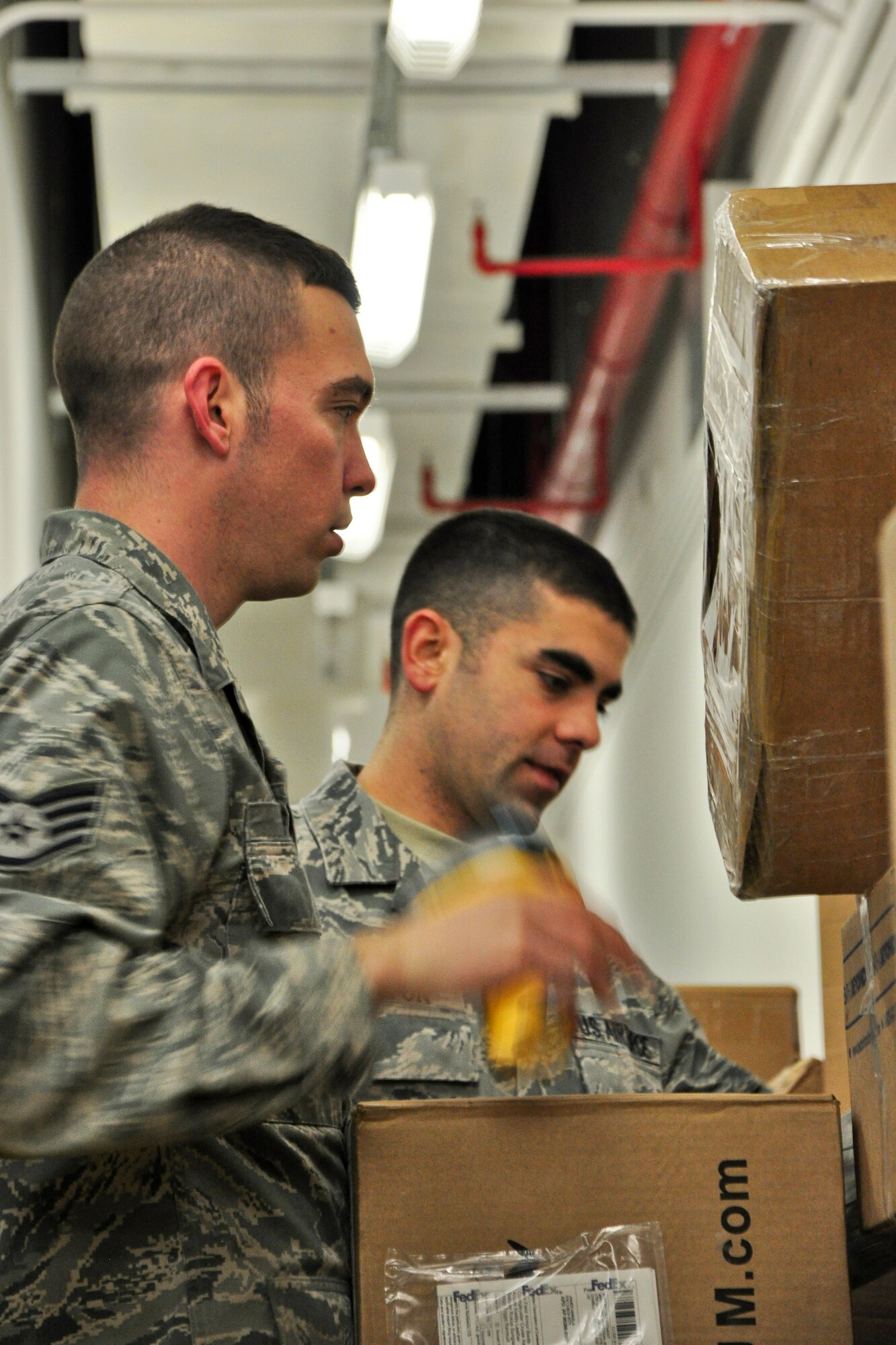 Staff Sgt. Nicholas Pompey and Senior Airman Charles Patton, both postal clerks with the 51st Communications Squadron, process some incoming packages Dec. 6, 2011. The Military Postal Service Agency here processes about 3,000 pieces of mail a day during the holiday season, and there is a lot that goes into “pitching” mail. (U.S. Air Force photo/Tech. Sgt. Chad Thompson)