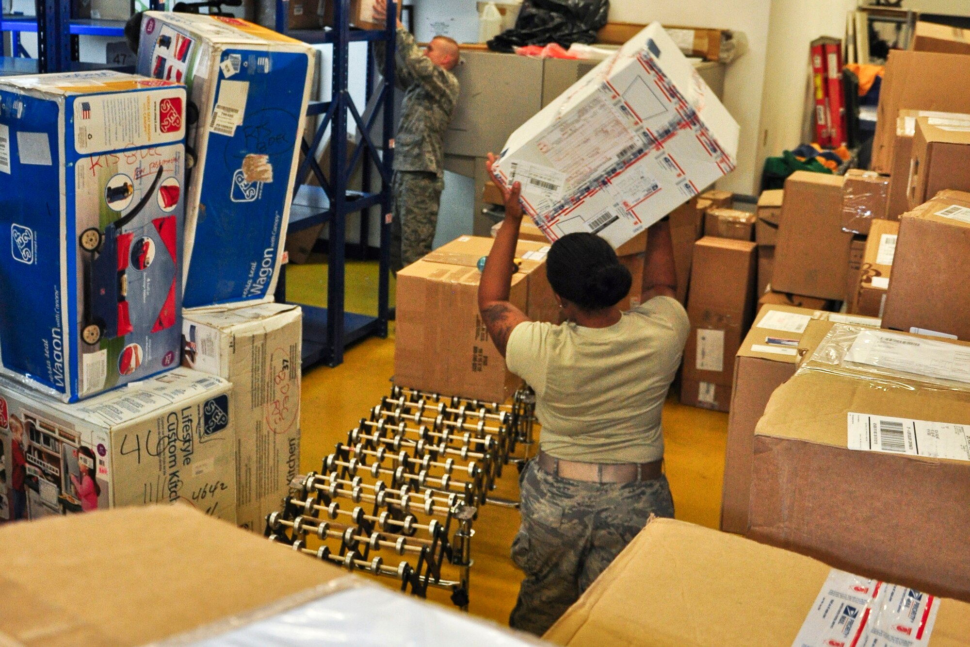 Senior Airman Meygan Freeney and Staff Sgt. Douglas Reedy, both postal clerks with the 51st Communications Squadron, work together to process and sort some packages here Dec. 6, 2011. The Military Postal Service Agency here processes about 3,000 pieces of mail a day during the holiday season. (U.S. Air Force photo/Tech. Sgt. Chad Thompson)