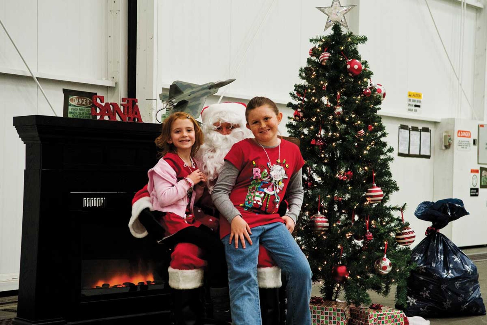 Kynzee and Kylee Coarsey, daughters of Air Force Staff Sgt. William Coarsey, 3rd Aircraft Maintenance Squadron crew chief, pose with Santa’s helper, Air Force Col. Terry Scott, 3rd Operations Group deputy commander, at the 90th Fighter Squadron Saturday. Santa’s helper visited in an F-22 Raptor. (U.S. Air Force photo/Staff Sgt. Zachary Wolf)