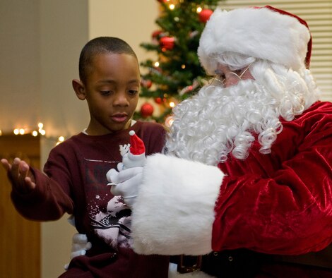 Santa hands Trabeon Wilcher, 7, a toy after hearing what Wilcher wanted for Christmas. Children of all ages were able to sit on Santa's lap during Malmstrom holiday festivities. (U.S. Air Force photo/Beau Wade)