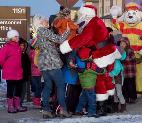 Children surround Santa, greeting him with hugs and smiles upon his arrival via firetruck to the tree lighting ceremony. Sparky the Fire Dog came along for the ride. (U.S. Air Force photo/Beau Wade)