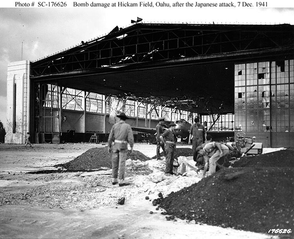 Bomb damage to Hangars 15-17 and 11-13 at Hickam Field, Oahu, at 5PM on Dec. 7, 1941. In the right foreground is a machine gun emplacement in a bomb crater.  A Douglas B-18 bomber is visible inside the badly damaged hangar. (Courtesy Photo/Air Force Historical Research Agency)