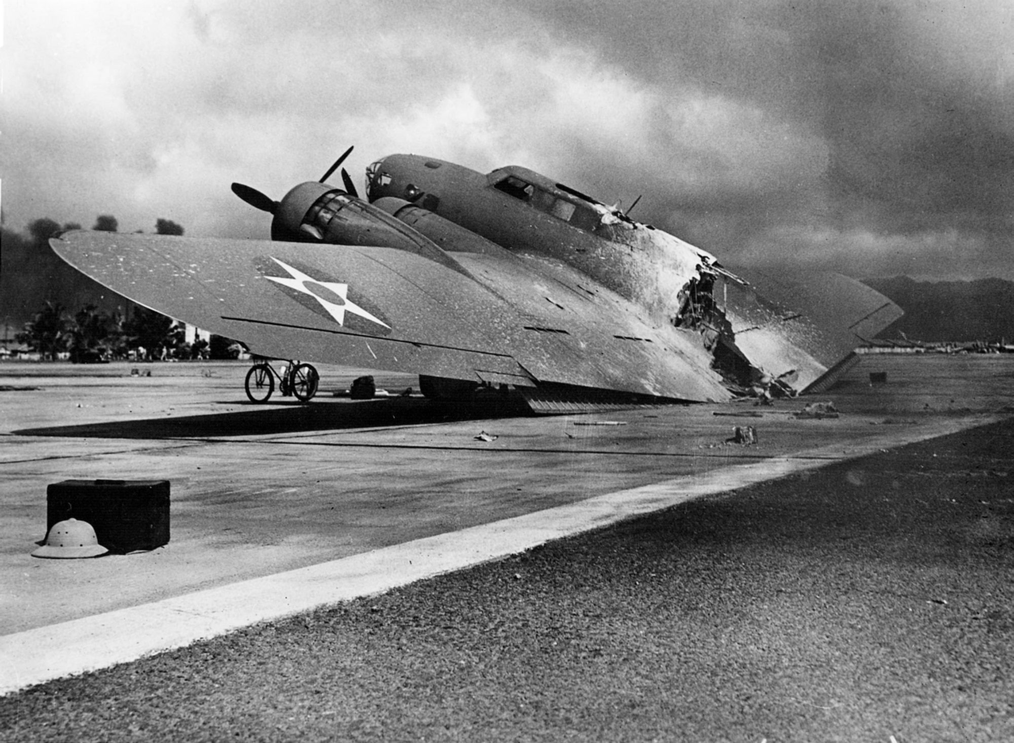 A burned U.S. Army Air Corps Boeing B-17C Flying Fortress (s/n 40-2074) rests near Hangar 5, Hickam Field, Hawaii, on 7 December 1941. It was one of 12 flown to Hickam from Hamilton Field, Calif., and arrived during the attack. On its final approach, the aircraft’s magnesium flare box was hit by Japanese strafing and ignited. The burning plane separated upon landing. The crew survived the crash, but a flight surgeon was killed by strafing as he ran from the burning wreck. (Courtesy Photo/National Archives and Records Administration)