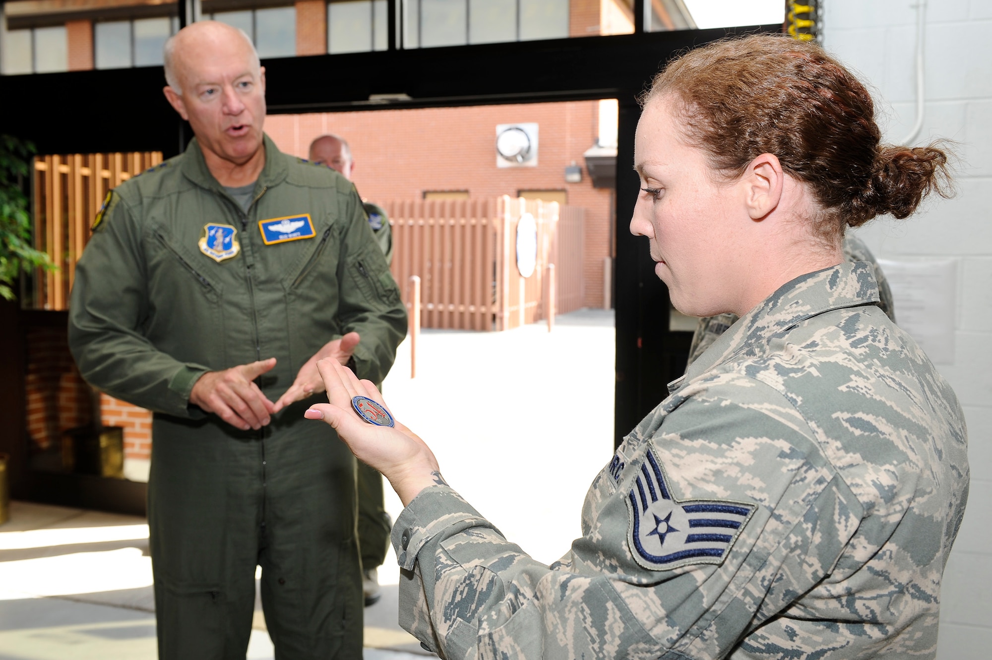 U.S. Air Force Staff Sgt. Bethany Tolley, 461st Aircraft Maintenance Squadron, receives a coin for outstanding performance from Lt. Gen. Harry Wyatt III, Air National Guard director, Robins Air Force Base, Ga., Dec. 05, 2011.  Tolley looked over the coin as Wyatt explained some unique aspects of the coin in reference to the Air National Guard.   (National Guard photo by Master Sgt. Roger Parsons/Released)
