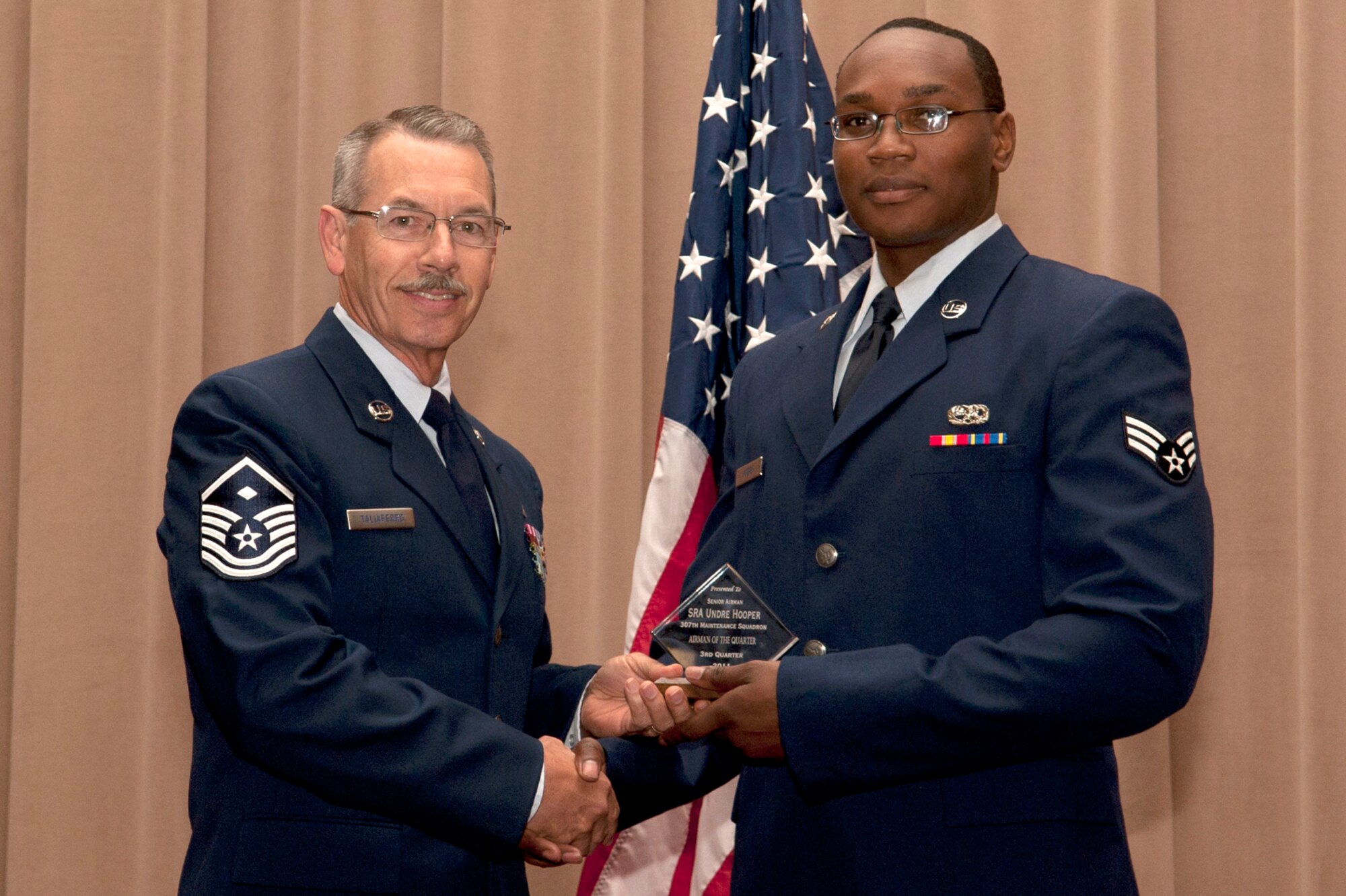 U.S. Air Force Master Sgt. James Taliaferro, 307th Security Forces Squadron First Sergeant, presents Senior Airman Undre Hooper with the Diamond Sharp award during an awards ceremony, Barksdale Air Force Base, La., Dec. 4, 2011. Hooper, assigned to the 307th Maintenance Squadron, received the award for being selected as the Airman of the Quarter for the period covering July to September 2011. (U.S. Air Force photo by Master Sgt. Greg Steele/Released)