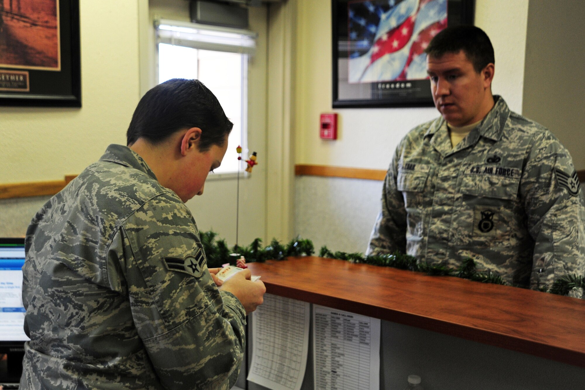 Airman 1st Class Brandie Johnson, 92nd Logistics Readiness Squadron, checks a customer’s government drivers license Dec. 1. “It’s important to make sure the individual requesting a government vehicle has the qualifications to operate the vehicle being checked out,” Johnson said. Dispatch can have as many as 20 customers a day, all needing to utilize government transportation. (U.S. Air Force photo/Airman 1st Class Taylor Curry)