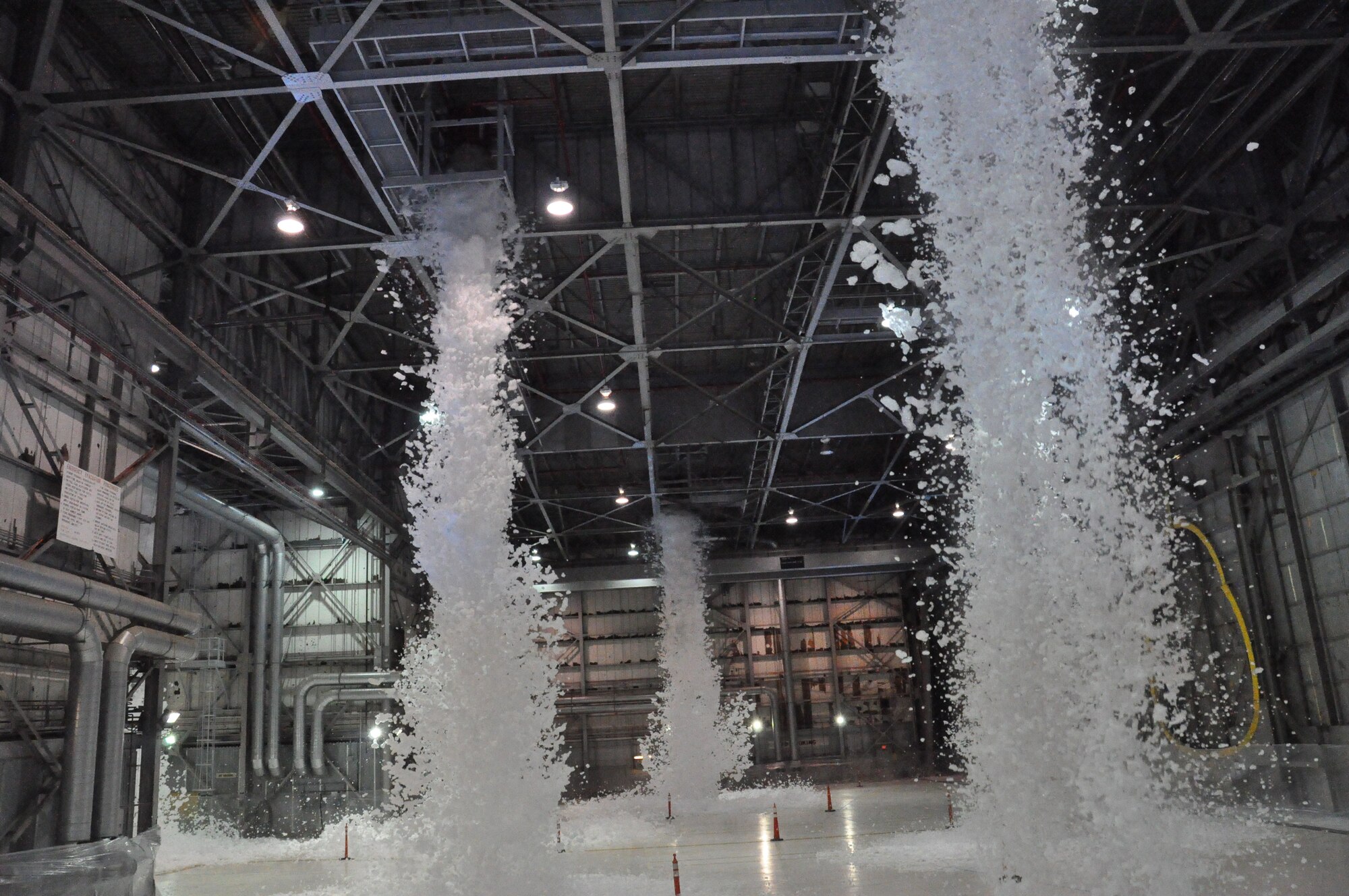 The high expansion foam begins to fall from the generators Tuesday during a test of the new fire protection system in Travis hangar 808. (U.S. Air Force photo/Airman Madelyn Ottem)