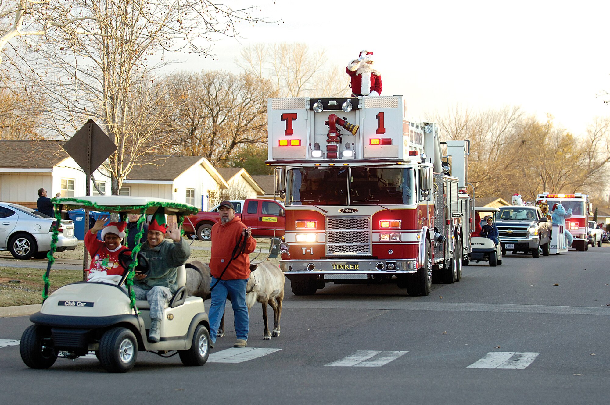 While the reindeer take a rest before Christmas Eve, Santa Claus rides through Base Housing atop the Tinker Fire Department’s ladder truck, waving to families lining the streets along the Dec. 1 parade route.  Tinker’s 72nd Air Base Wing Command Chief Master Sgt. Kevin Vegas and his wife Lori Johnson-Vegas also wave to the crowd as a stream of holiday-themed characters make their way to the Tinker Club for the annual tree-lighting and party. (Air Force photo by Margo Wright)