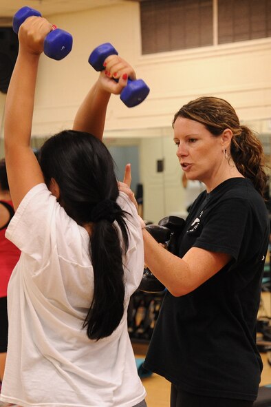 Karen Wink, BellaMorphosis group fitness instructor, corrects an attendee's form during target fit class on Seymour Johnson Air Force Base, N.C., Dec. 7, 2011. During group classes, certified instructors help participants with proper form to prevent injury and keep them on track with their goal. Wink is from New Zealand. (U.S. Air Force photo by Senior Airman Whitney Stanfield)