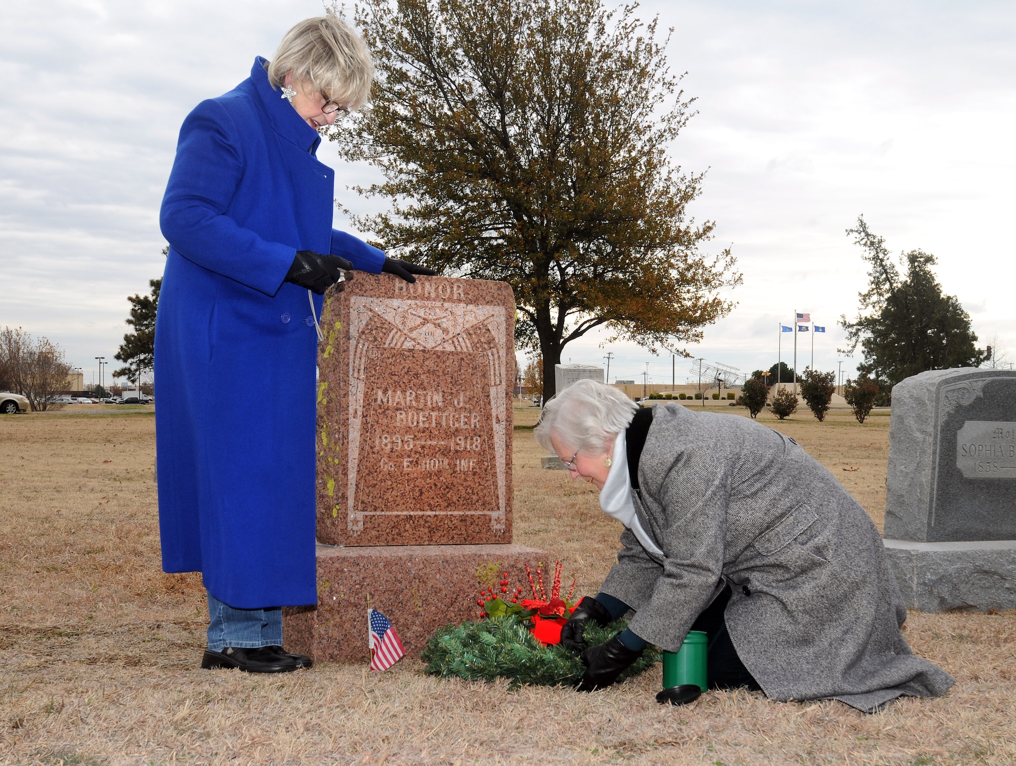 Joann Winters, left, and Ruth Johnson, kneeling, from the Malcolm Hunter Chapter of the Daughters of the American Revolution, secure a wreath at the grave of a World War I veteran buried in Kuhlman Cemetery at Tinker Air Force Base. The ceremony was held Monday in conjunction with Wreaths Across America Day, which will be observed Dec. 10 to honor the nation’s veterans at Arlington and in cemeteries across the country. (Air Force photo by David Faytinger)