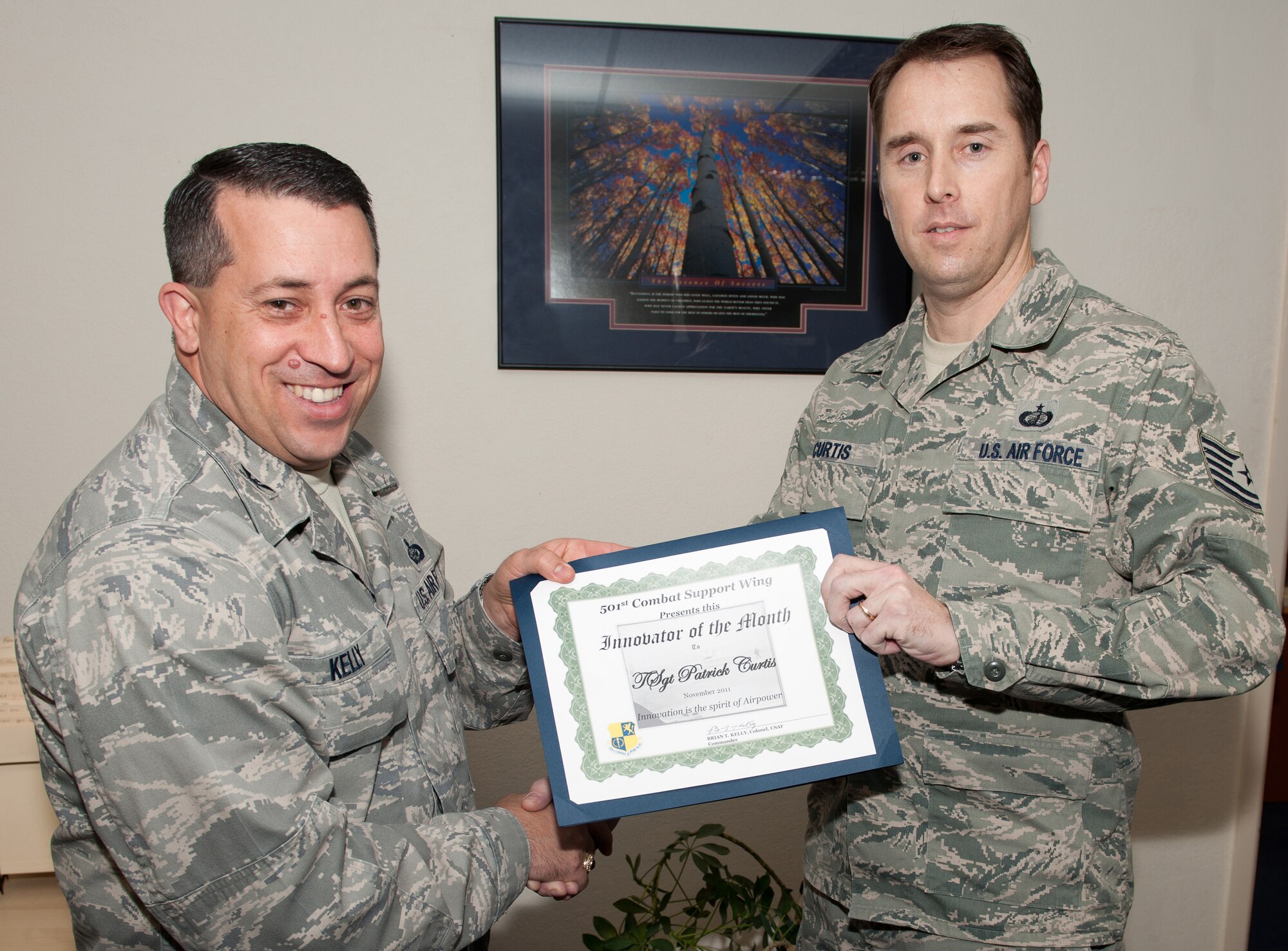 RAF ALCONBURY, United Kingdom - Col. Brian Kelly, 501st Combat Support Wing commander, presents the Innovator of the Month Award to Tech. Sgt. Patrick Curtis, 501st Combat Support Wing Finance Office. Curtis changed the process to fill out the civilian time sheet by making the process easier to use. (U.S. Air Force photo by Senior Airman Joel Mease)