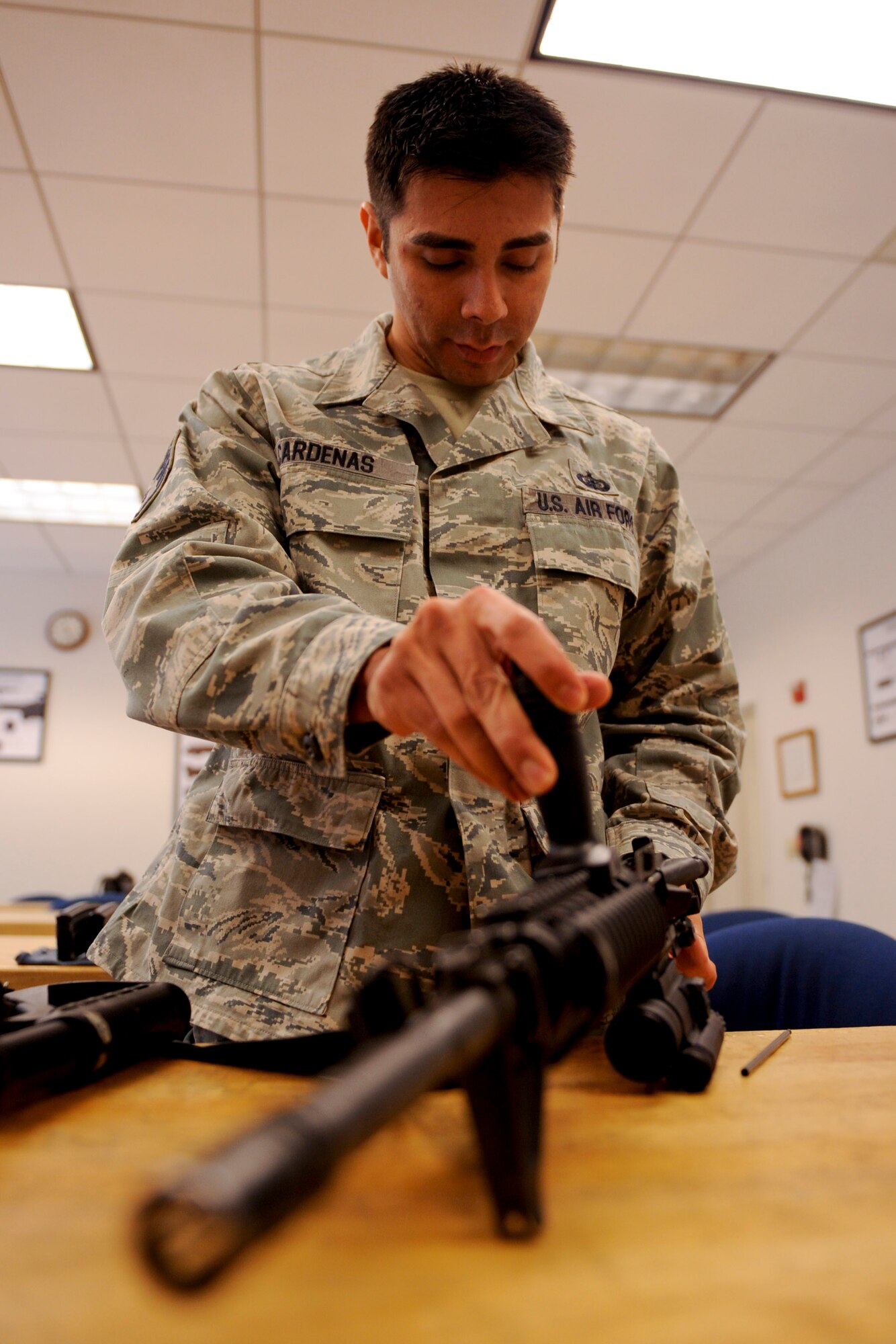 VANDENBERG AIR FORCE BASE, Calif. -- Staff Sgt. Anthony Cardenas, a 382nd Training Squadron resource advisor, disassembles an M4 carbine during the first class of the new Rifle Carbine Air Force Qualification course here Tuesday, Dec. 6, 2011. The new course, in which Airman fire nearly double the amount of rounds of the previous course, contains both basic firing positions (prone, sitting, kneeling, standing) and advanced tactical movements. (U.S. Air Force/Staff Sgt. Levi Riendeau)
