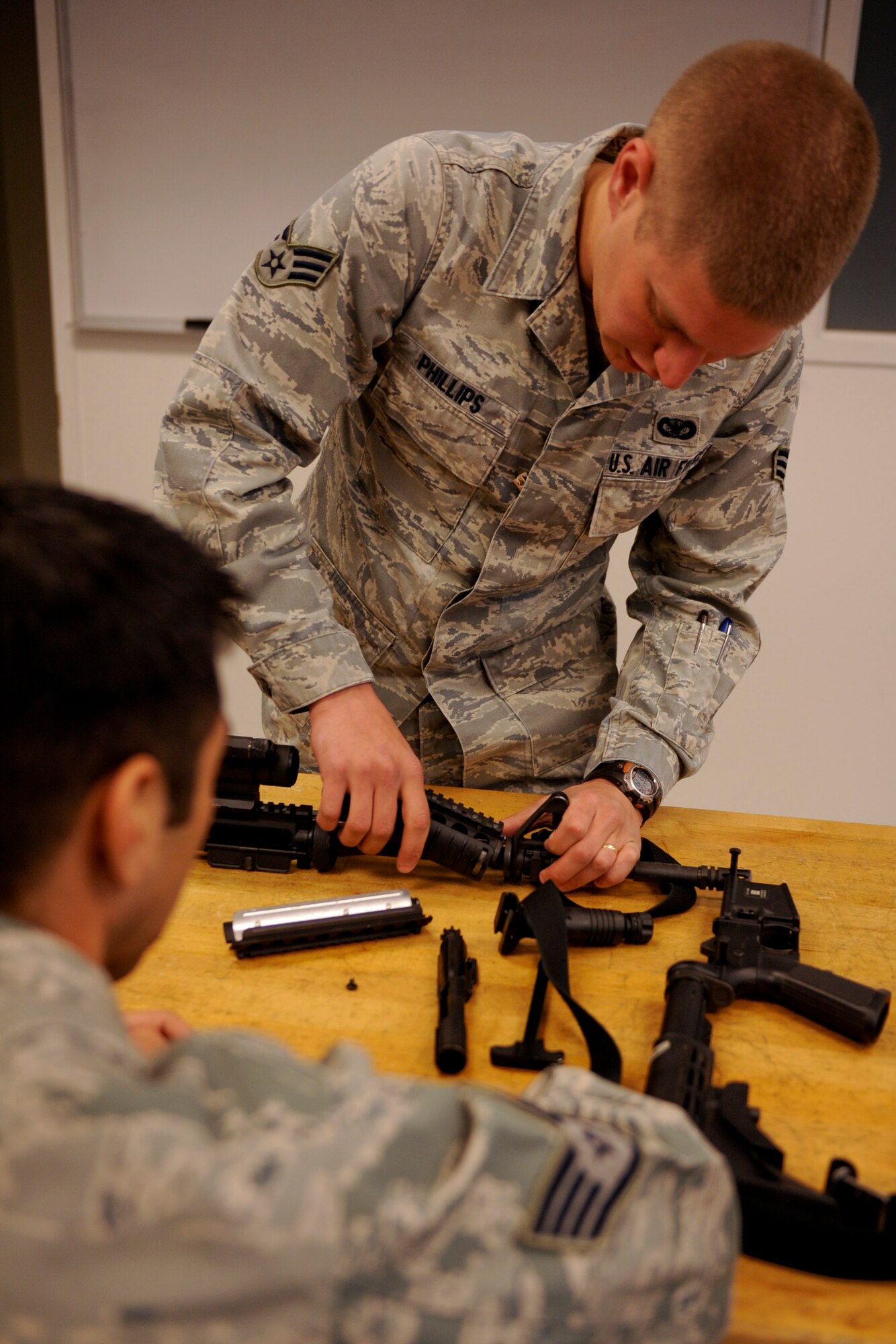 VANDENBERG AIR FORCE BASE, Calif. -- Senior Airman Jesse Phillips, a 30th Security Forces Squadron Combat Arms instructor, assists a student with the disassembly of an M4 carbine during the first class of the new Rifle Carbine Air Force Qualification course here Tuesday, Dec. 6, 2011. The new course, in which Airman fire nearly double the amount of rounds of the previous course, contains both basic firing positions (prone, sitting, kneeling, standing) and advanced tactical movements. (U.S. Air Force/Staff Sgt. Levi Riendeau)