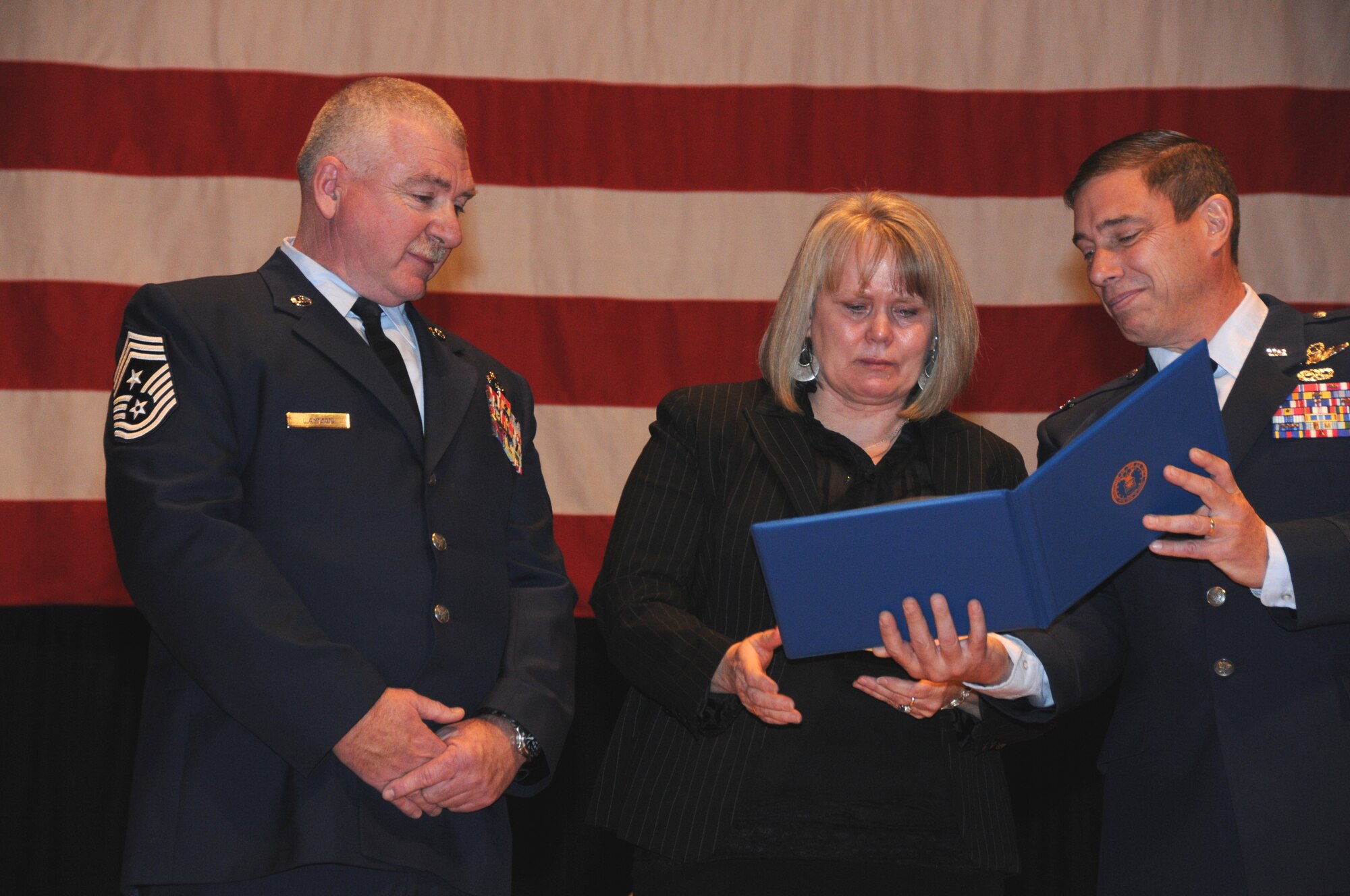 148th Fighter Wing Command Chief Master Sergeant Michael Layman watches as his wife Theresa receives the  Military Spouse Medal from Col. Frank H. Stokes, 148th Fighter Wing Commander during a ceremony that was held Dec. 4, 2011 in Duluth, Minn.  The medal was given to Mrs. Layman for her unwavering support of her husband during his military career.  National Guard photo by Tech. Sgt. Brett Ewald)