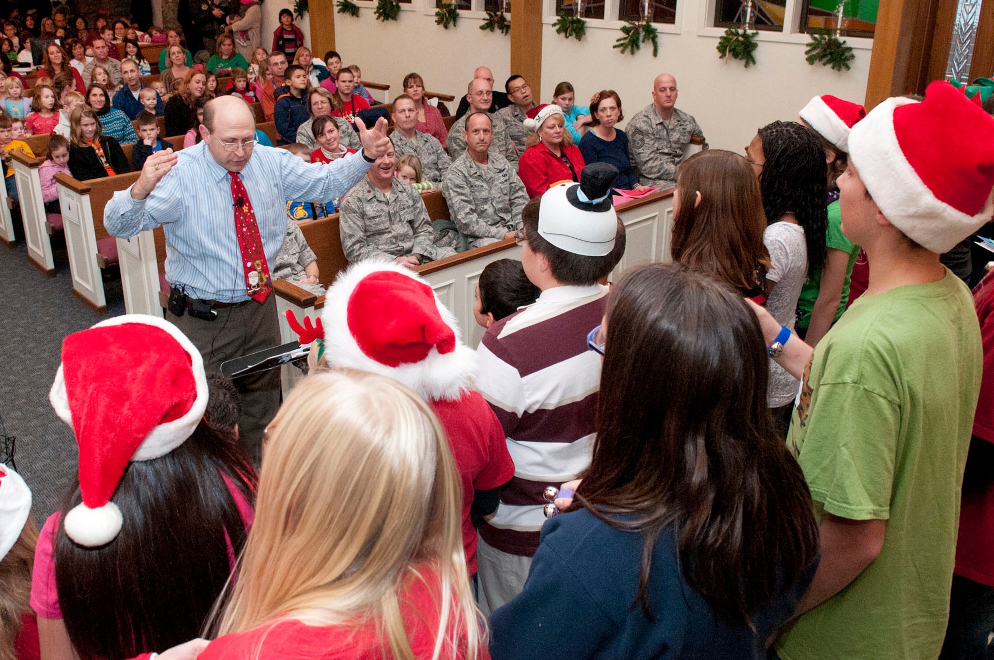 HANSCOM AIR FORCE BASE, Mass. – Howard Worona, Hanscom Middle School Music and After School Music Programs director, leads Hanscom youth in singing holiday songs just before the Christmas Tree Lighting ceremony at the base chapel Dec. 1. The event also included performances by the Hanscom Bell Choir and Band of Liberty, as well as a chance enjoy refreshments and take photos with Santa.(U.S. Air Force photo by Mark Wyatt)