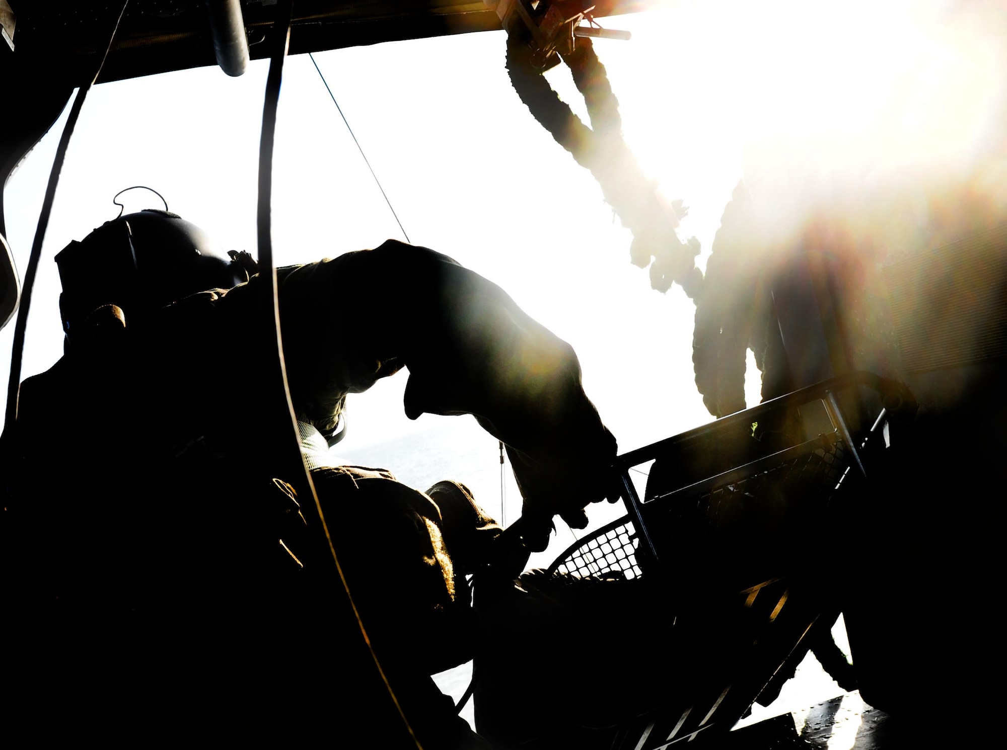 U.S. Air Force Staff Sgt. Dane Hatley, 33rd Rescue Squadron flight engineer, lowers a litter down into the water during a training mission in Okinawa, Japan, Dec. 7, 2011. The 33rd RQS took part in the 12th annual exercise Cope Angel, which is a bilateral exercise with Japan Air Self Defense Force. (U.S. Air Force photo by Airman 1st Class Brooke P. Beers/Released)