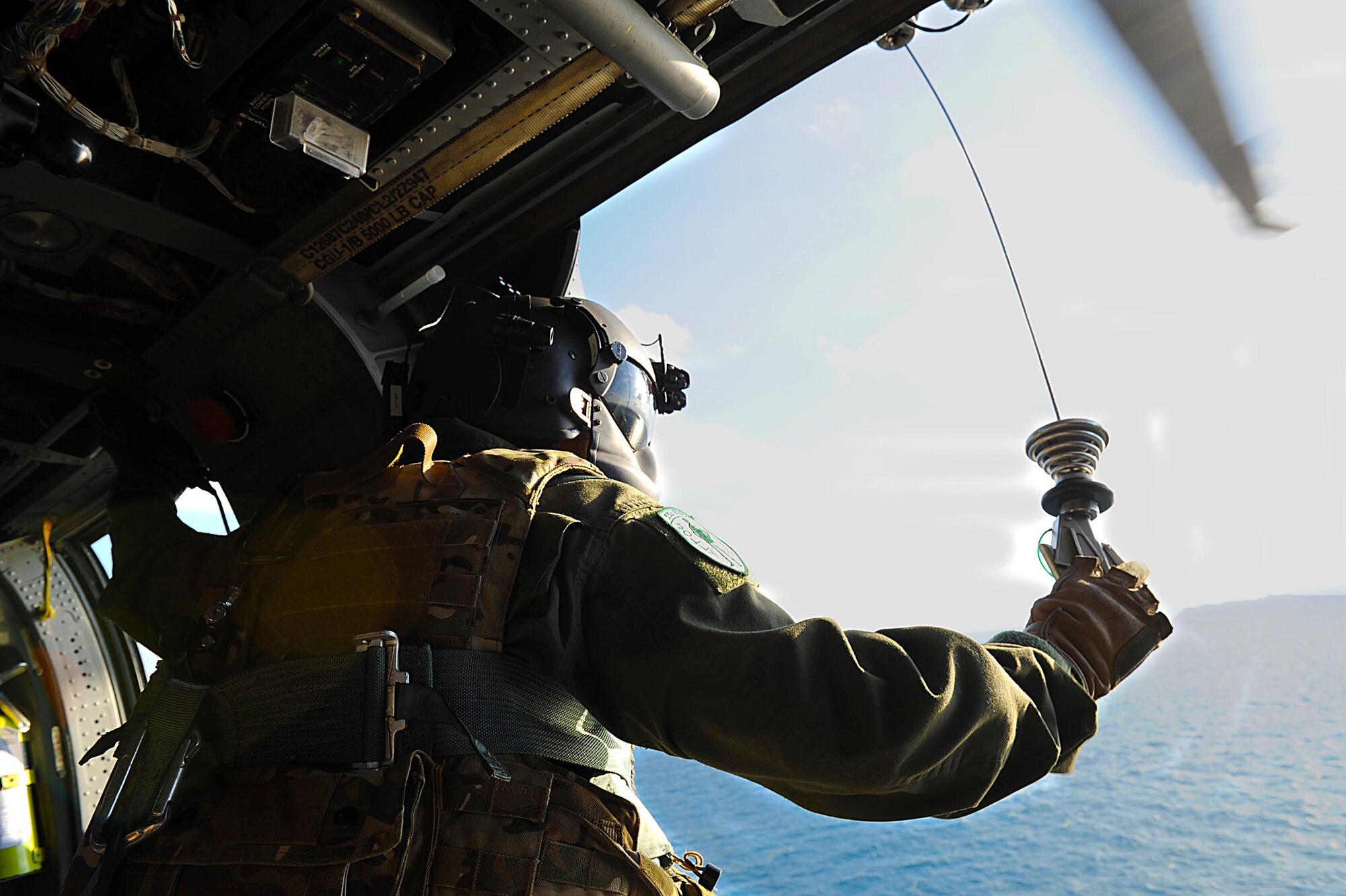 U.S. Air Force Staff Sgt. Dane Hatley, 33rd Rescue Squadron flight engineer, prepares the hoist during training in Okinawa, Japan, Dec. 7, 2011. The 33rd RQS took part in the 12th annual exercise Cope Angel; the training took place both on land and over water. (U.S. Air Force photo by Airman 1st Class Brooke P. Beers/Released)