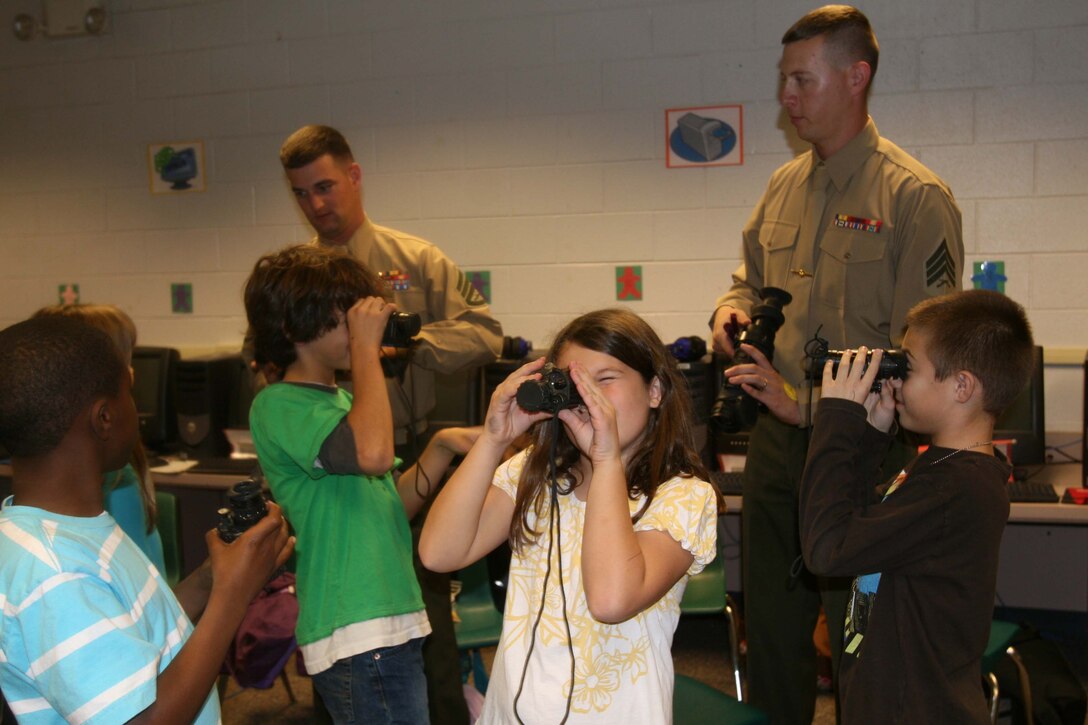 (left) Staff Sgt. Zachary R. Stelke, a scout platoon sergeant and Sgt. Timothy C. Bordan, a scout section leader, from 2nd Tank Battalion, 2nd Marine Division, teach a class on night vision equipment at Jacksonville Commons Elementary School, N.C., Dec. 9. Stelke and Bordan were two Marines of approximately five who visited the school’s children to teach them about some of the equipment Marines use.