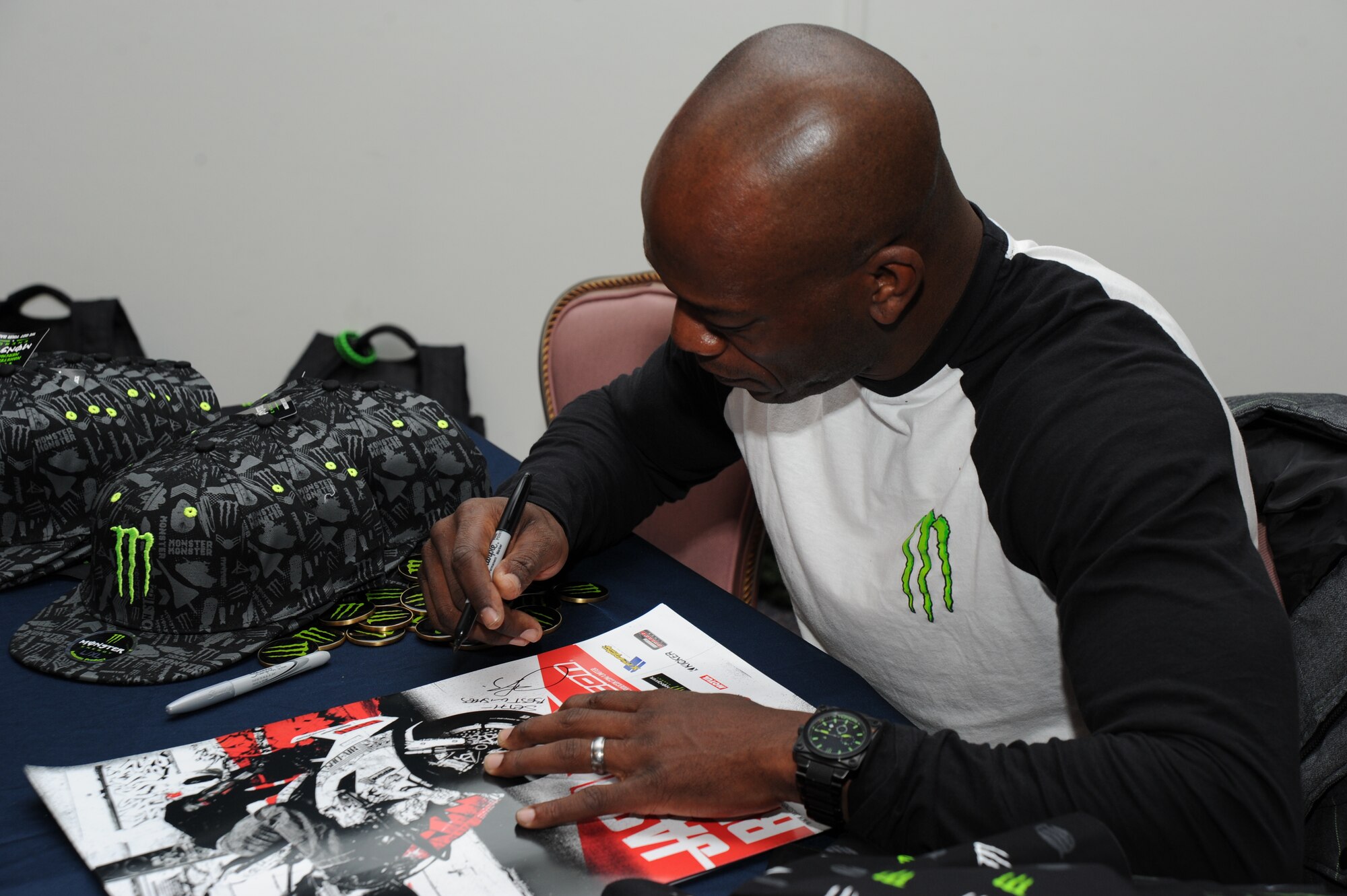 Jason Britton, sports bike free-style rider, give thanks to the servicemembers and sign autographs Dec. 8 at the USO pizza party on Joint Base Andrews, Md. “Being a sponsor of Monster [energy drink], they utilize athletes to give thanks to the troops,” said the movie stunt biker who has 15 years of professional biking experience. (U.S. Air Force photo by Staff Sgt. Christopher Ruano)