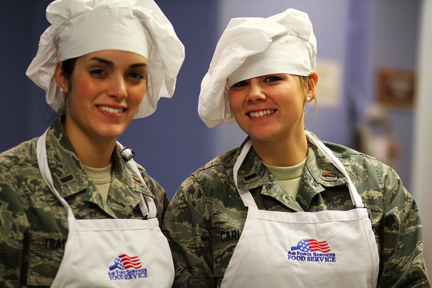 MINOT AIR FORCE BASE, N.D. -- 2nd Lt.s Amanda Trainor and Tavia Carlson, 5th Civil Engineer Squadron, volunteers their time at the Dining Facility here to serve young enlisted Airmen meals. The officers provide this monthly community service as part of the Minot AFB Company Grade Officers’ Council outreach.  (U.S. Air Force photo/ Capt. Jon Arceta)