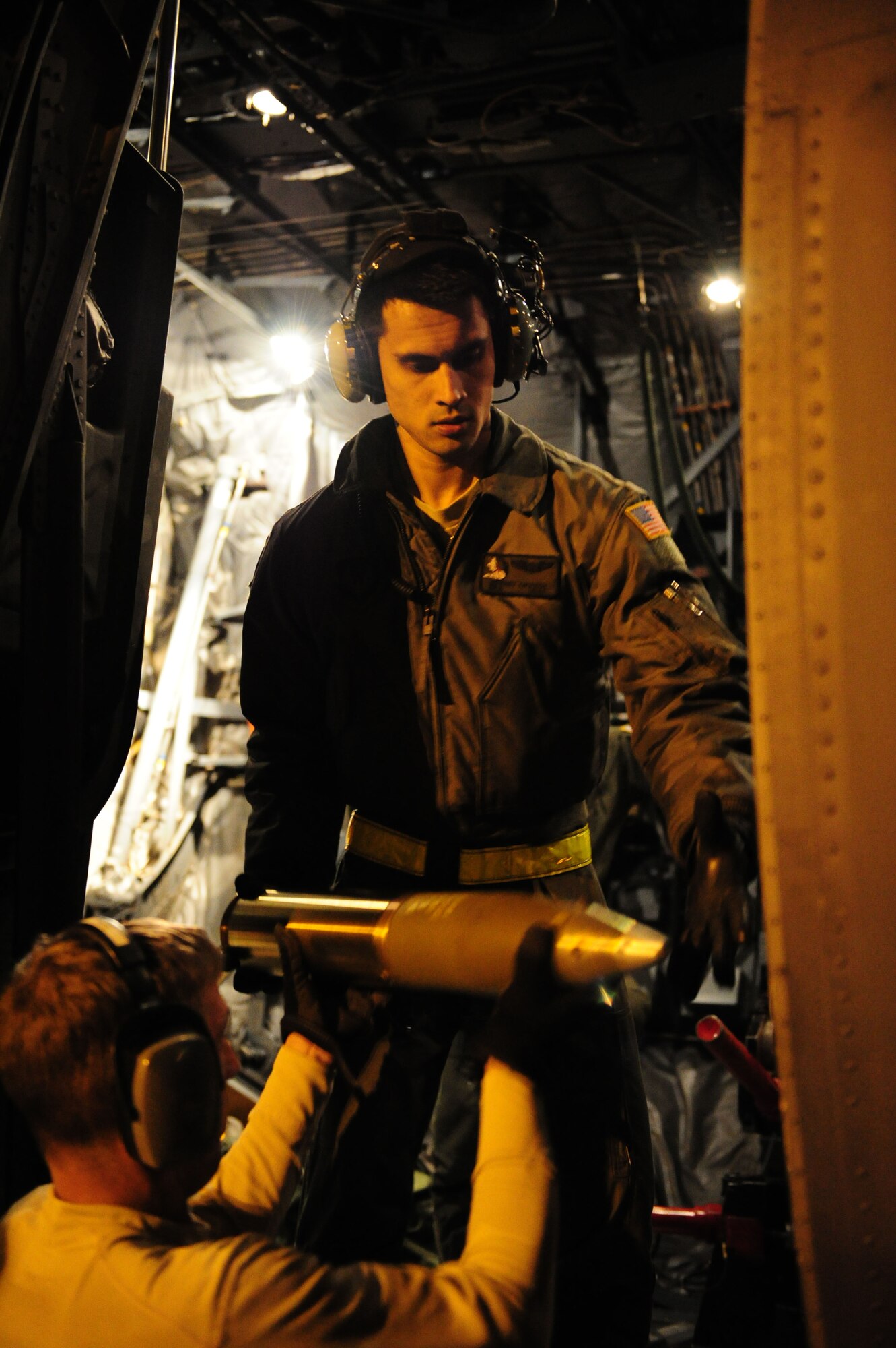 U.S. Air Force Airman 1st Class Jeffery Craven, 4th Special Operations Squadron aerial gunner, loads a newly refurbished 105 millimeter target practice shell into an AC-130 Gunship on the flight line on Hurlburt Field Fla., Nov. 30, 2011.  The ammunition loading process must be done quickly to conserve fuel. (U.S. Air Force photo/Airman 1st Class Gustavo Castillo)(Released)
